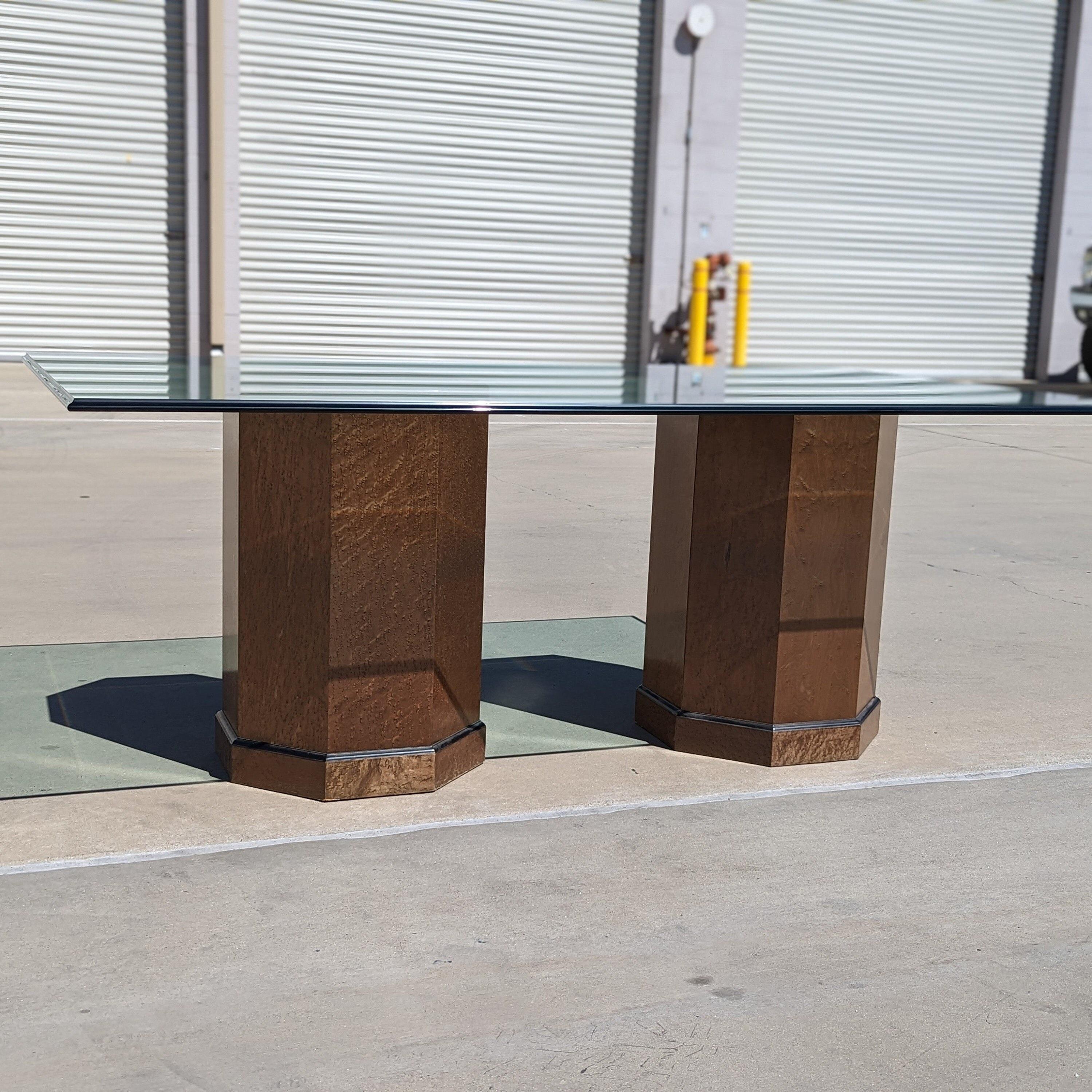 An elegant Postmodern dining table by Bernhardt, featuring a sleek glass top and distinctive birdseye maple pedestal bases, embodying unique design from the 1980s.

This table combines bold architectural forms with rich natural materials, creating a