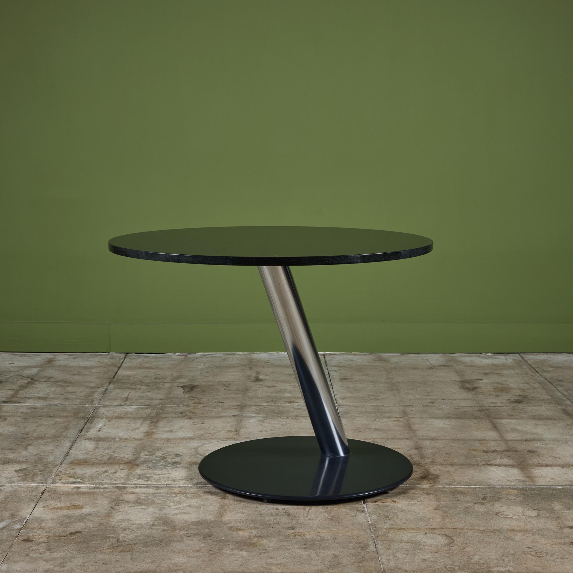 Table de bistrot en granit, C.C., USA. Le plateau de la table ronde en granit noir est moucheté de gris. Le plateau de la table repose sur une barre de support tubulaire angulaire en acier inoxydable chromé avec une base ronde en