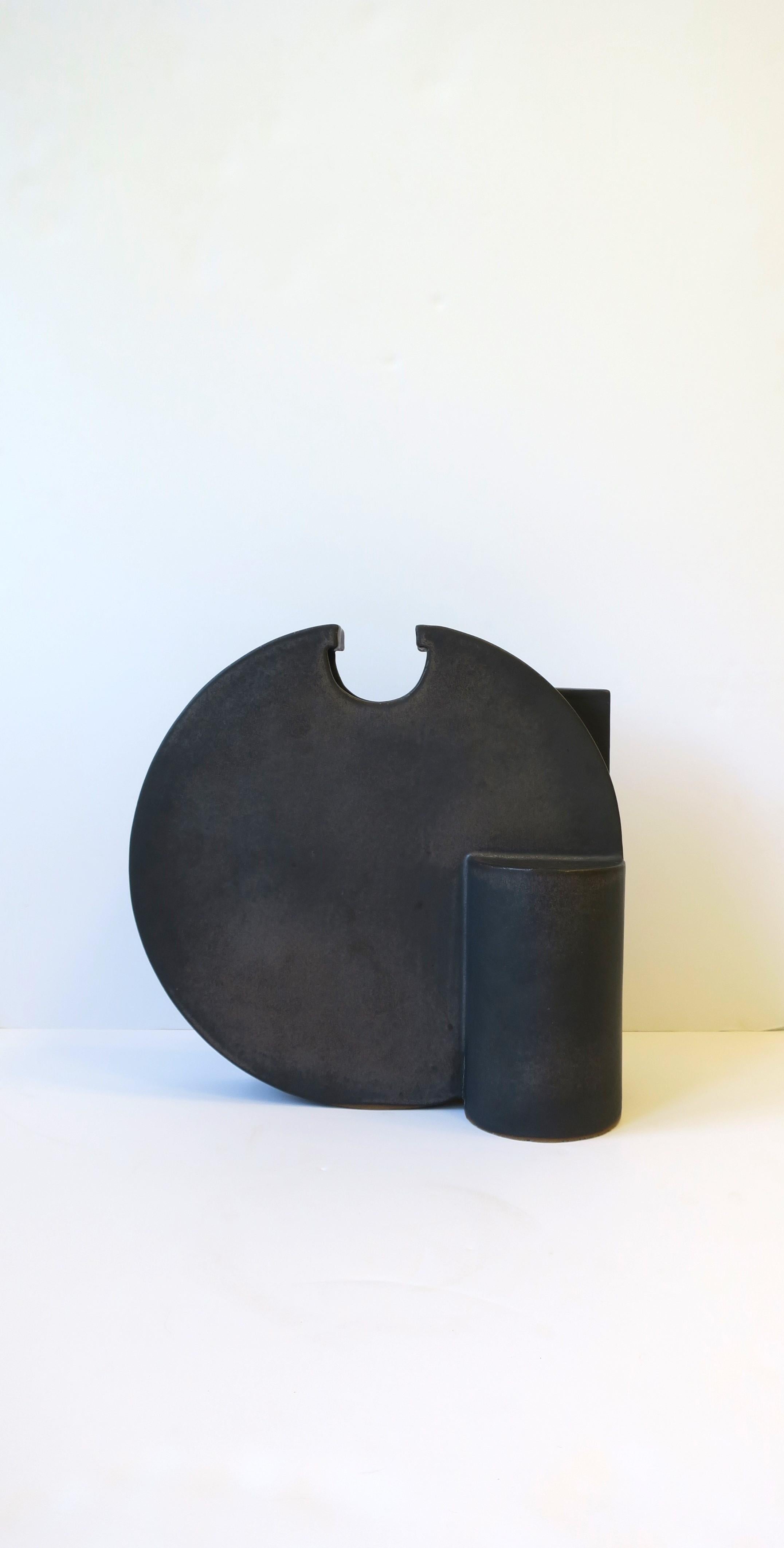 A beautiful and substantial Postmodern black charcoal sculpture vase, circa late-20th century. Piece is clay pottery with a black charcoal matte finish, with a round, cylindrical, asymmetric design. Designers mark on underside. For size perspective