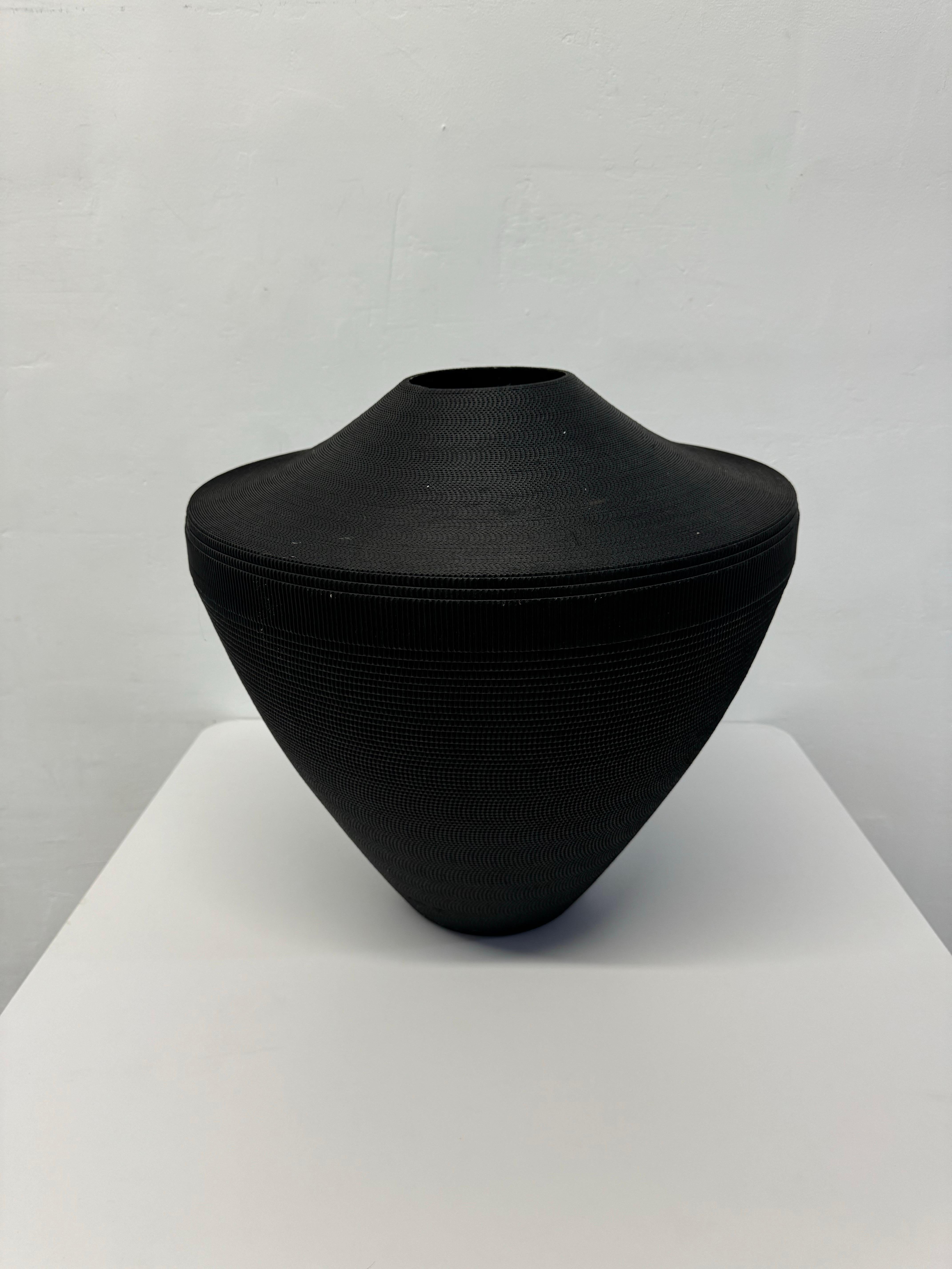 Corrugated cardboard vase rendered in matte black by Flute, Chicago circa 1980s.  Vase sits at a slight angle. Best to use with dried arrangements.