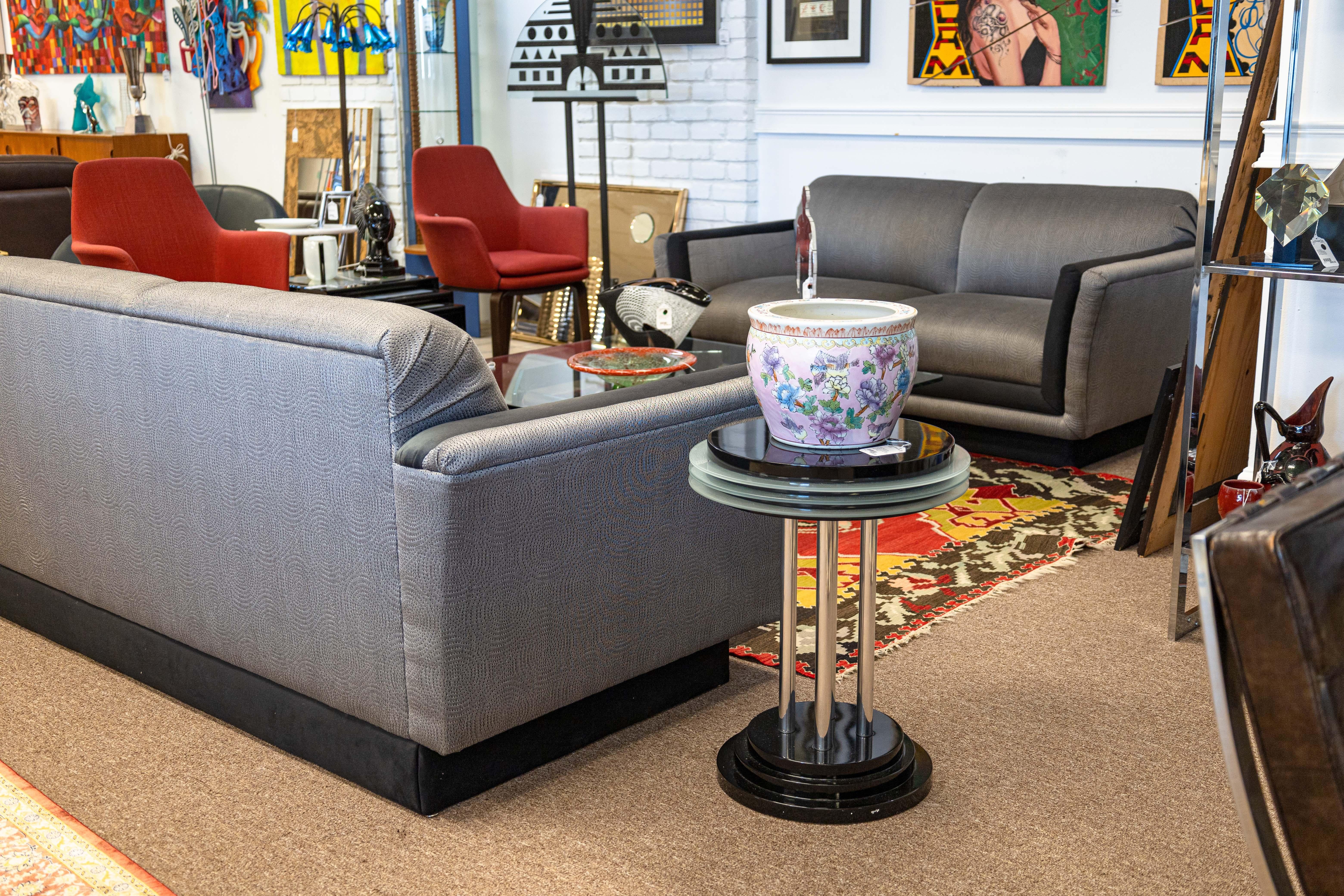 A postmodern Memphis style pedestal side end table. This gorgeous postmodern table features all the classic Memphis motifs and design materials. The table top and the tapered base features a black glossy lacquered finish. The table top features