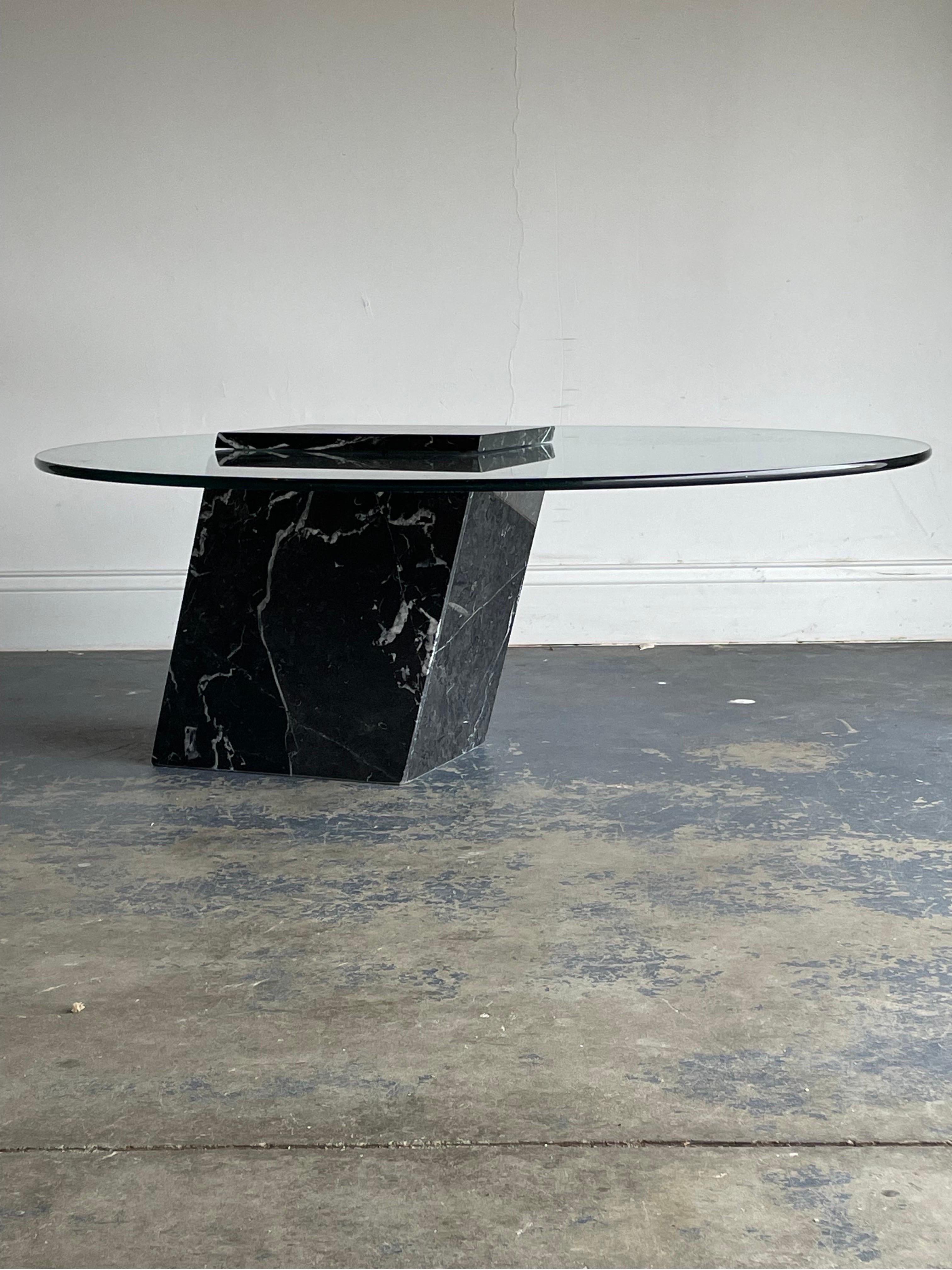 Wonderful modernist coffee table in the manner of Brueton. Features a slanted blacked marble base, atop sitting a thick 0.5