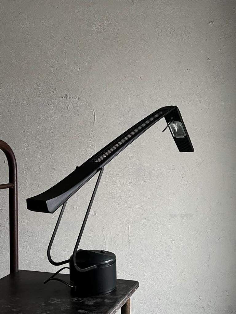 Black metal postmodern halogen desk lamp with rotating head and a heavy metal+plastic base. There are two lighting modes. Due to the rotating head, you may light up the space in 360º. The design reminds Mario Barbaglia “Dove” lamp. I have the same