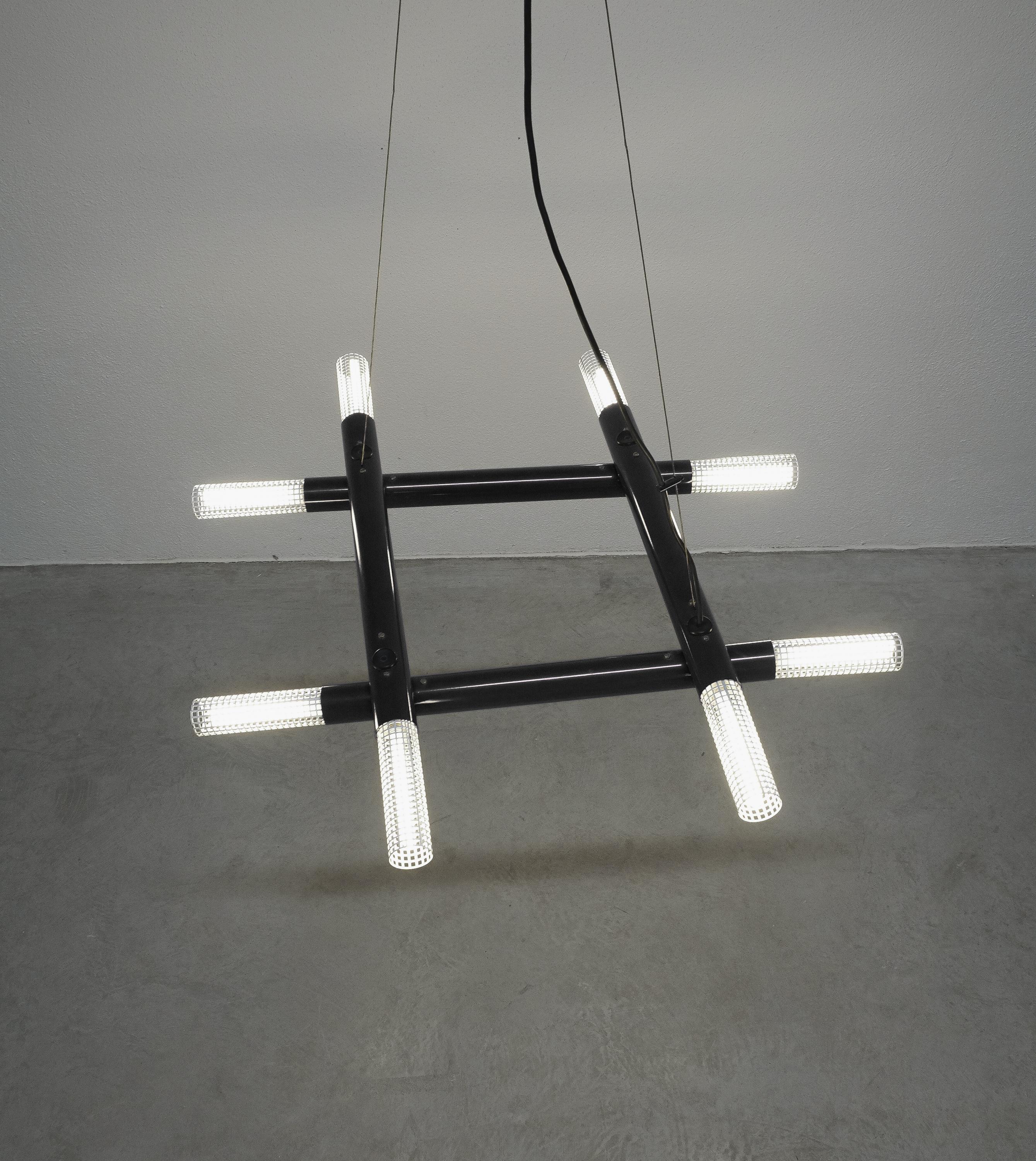 Postmodern black metal atomic chandelier, circa 1980

Cool architectural contemporary chandelier from the 1980s, Italy. It illuminates with 8 bulbs hidden behind white perforated metal diffusers. It can be adjusted pivoting the black tubes. The