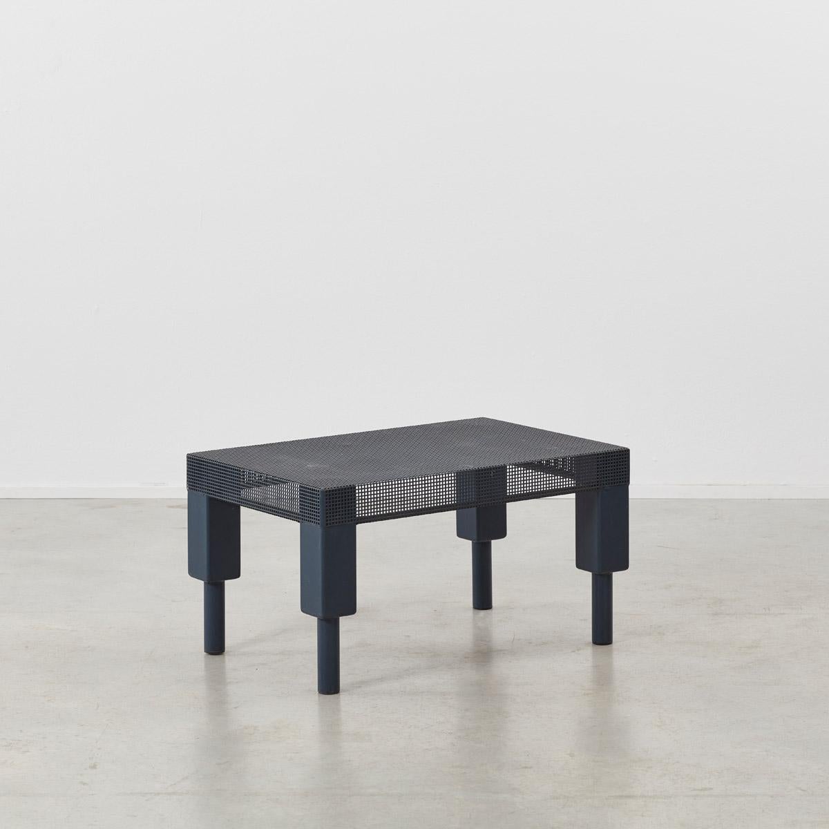 This Postmodern table is made from folded perforated metal sheeting, in a dark matte blue paint. The table has considerable strength and can be used as a side table or a small coffee table. The piece is in good structural condition with minor