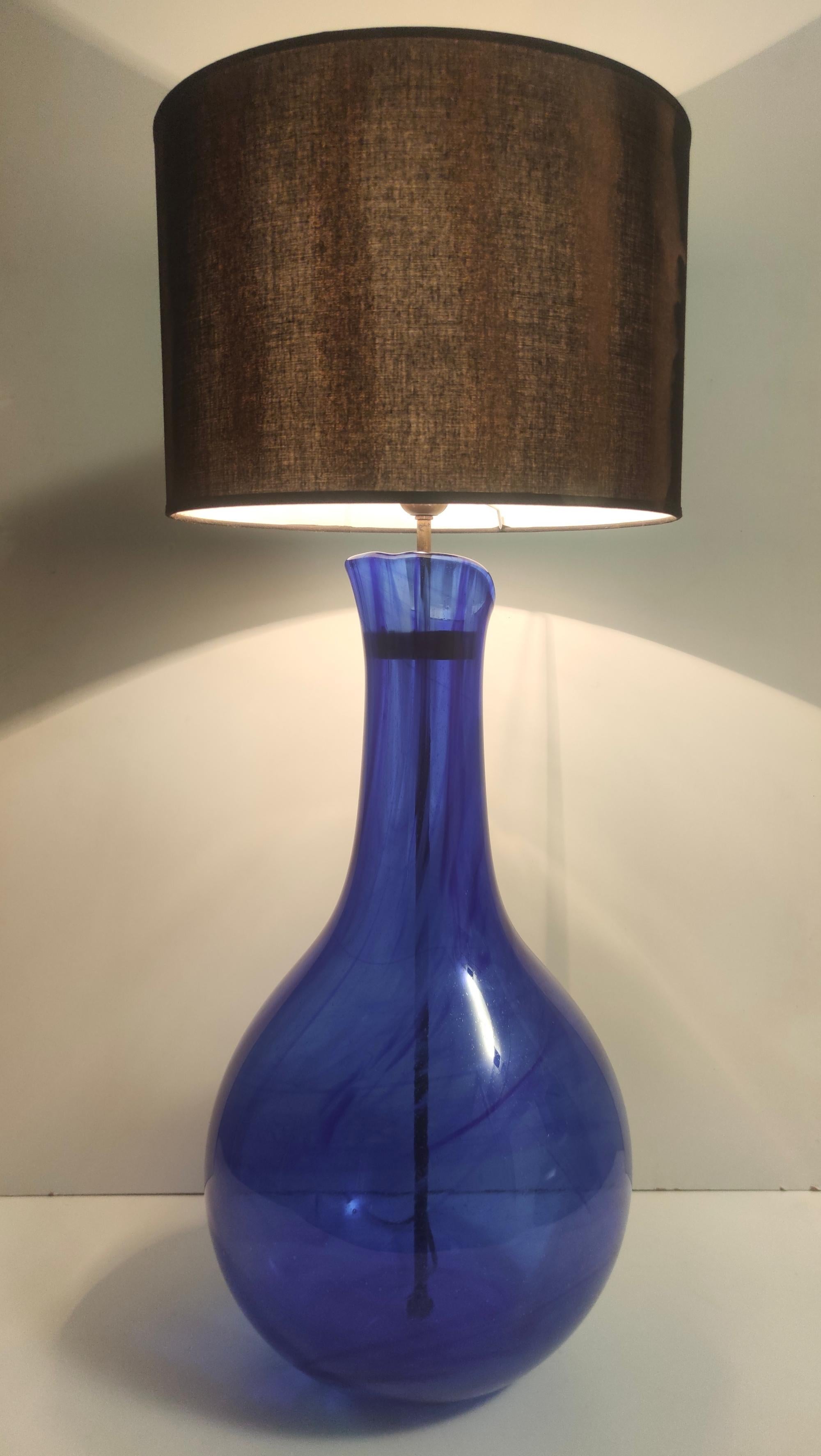 Made in Italy, 1960s - 1970s.
The lamp features a blue Murano glass base, that has bubbles and pleasant transparencies and veins due to the handcraft process. 
The wiring has been renewed and is compatible with the US.
It might show slight traces of