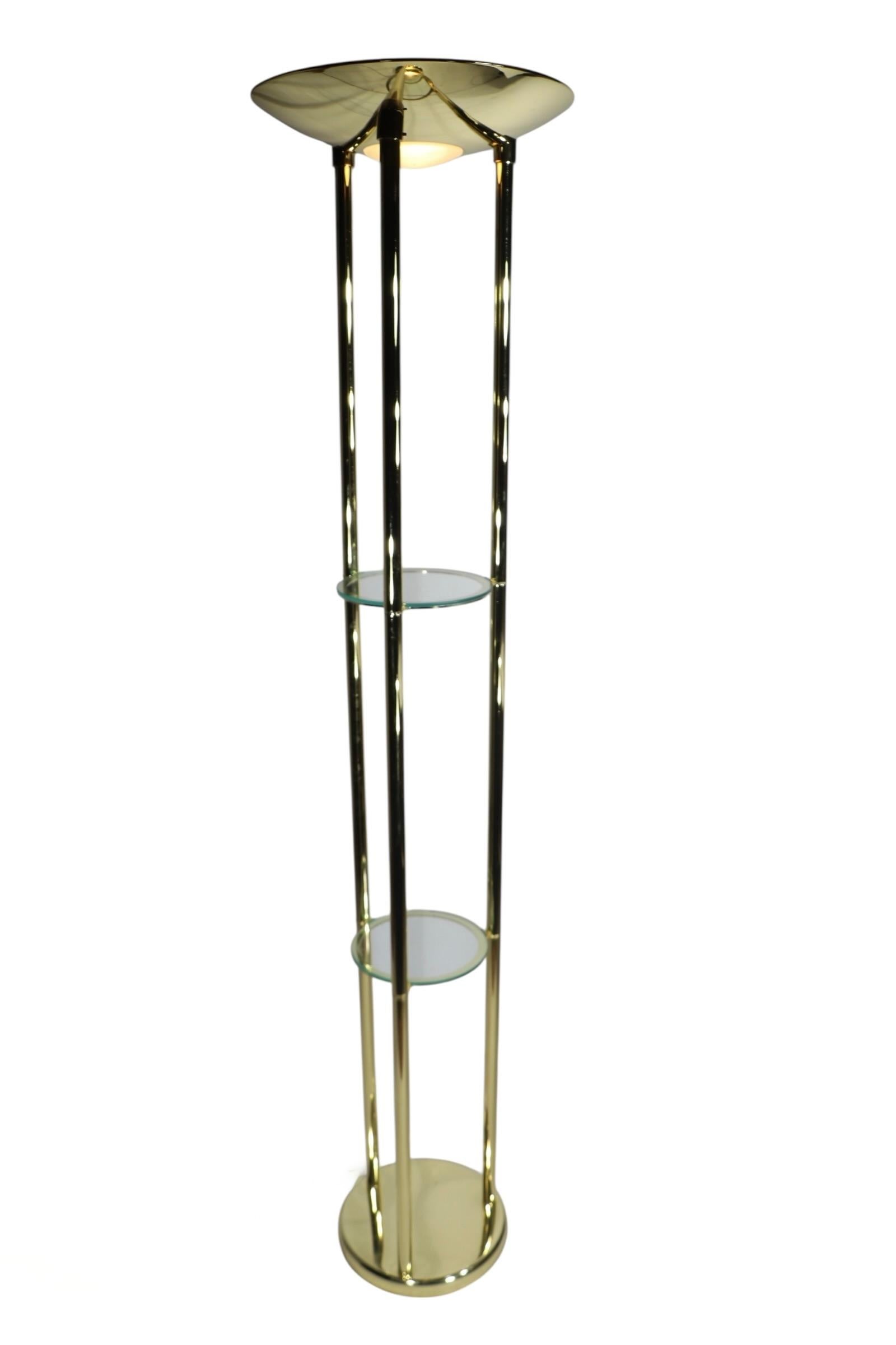 Excepcional lámpara de pie uplight torchiere posmoderna, de estilo Hollywood Regency, en excelente estado, original, limpia y en funcionamiento. Esta insólita lámpara presenta dos estantes interiores para exponer objetos pequeños, bajo la pantalla