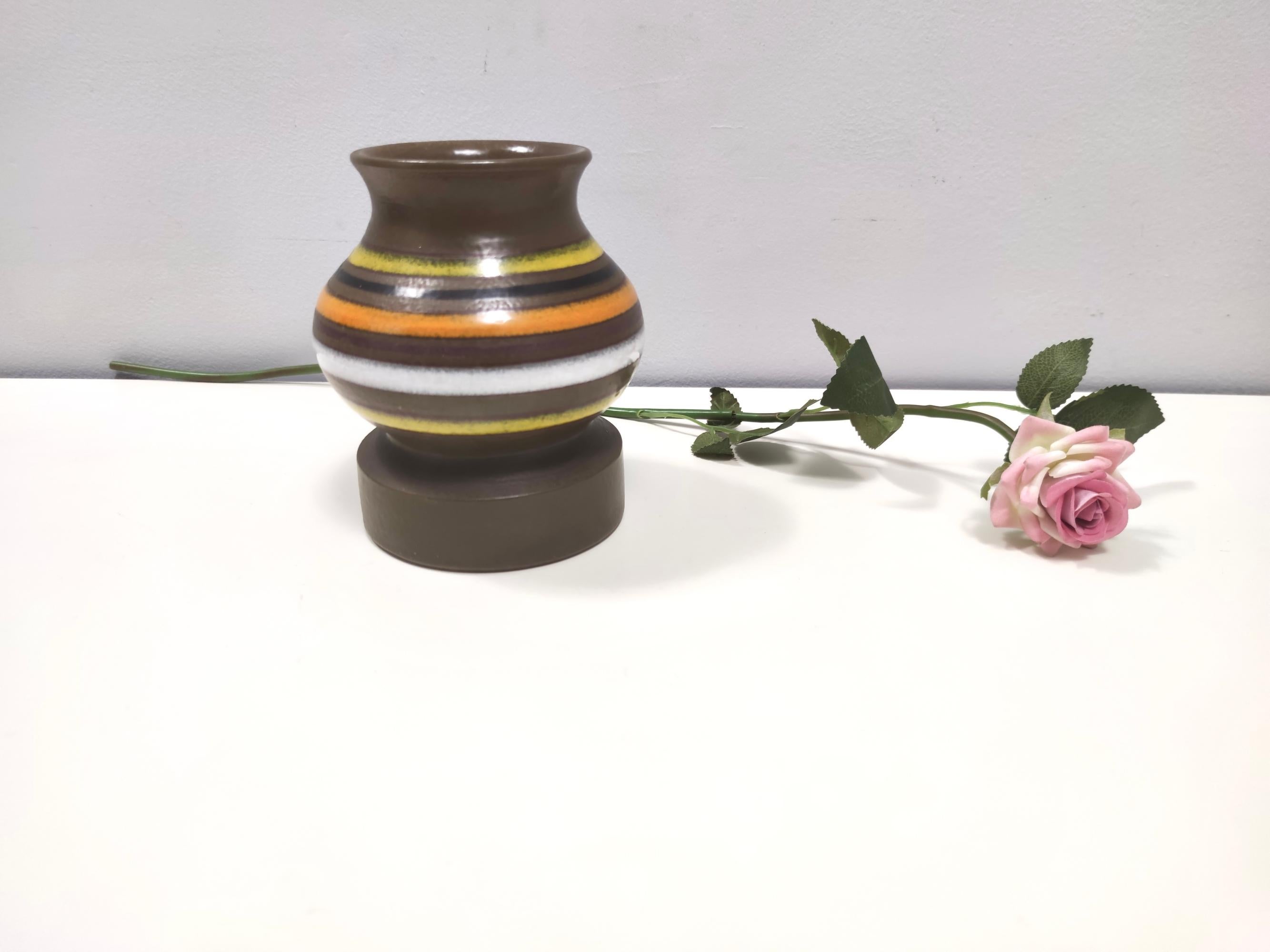 Fabriqué en Italie, années 1970. 
Il s'agit d'un vase en faïence émaillée brune avec un motif linéaire de différentes couleurs.
Il s'agit d'un article vintage, qui peut donc présenter de légères traces d'utilisation, mais qui peut être considéré