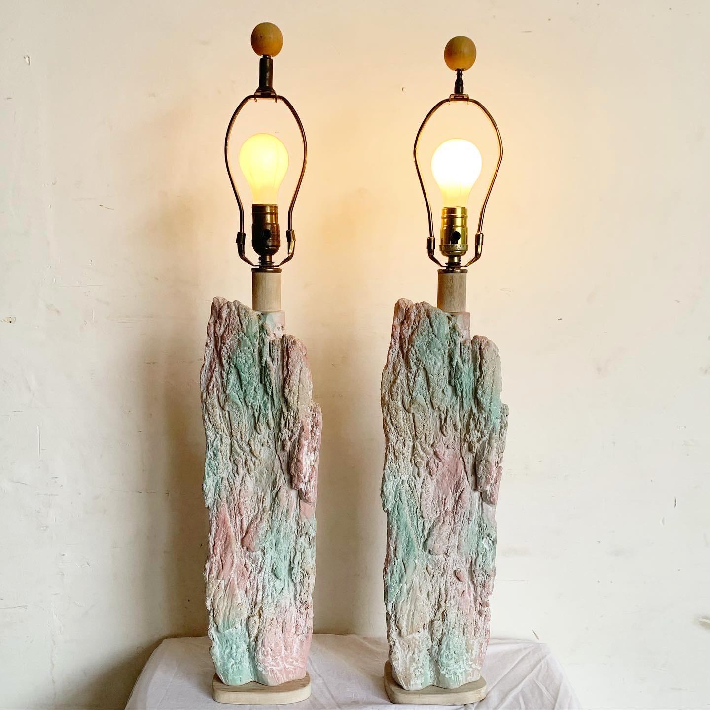 Step back into the 1980s with the Postmodern Brutalist Pink and Green Faux Stone Three Way Table Lamps. This pair captures the vibrant artistry of the era with a hand-painted scene of a lone wolf against a moonlit mountain backdrop. Standing at