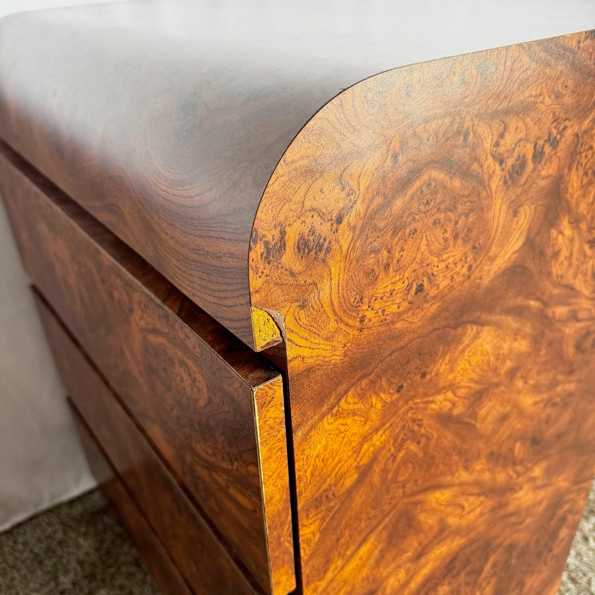 Mejora los interiores con esta mesilla de noche postmoderna de madera burl: curvas en cascada, textura de madera burl, tiradores dorados y elegancia postmoderna.
 

 Un desconchón en el lateral como se ve en las fotos. 
 

 Vendemos artículos tal y