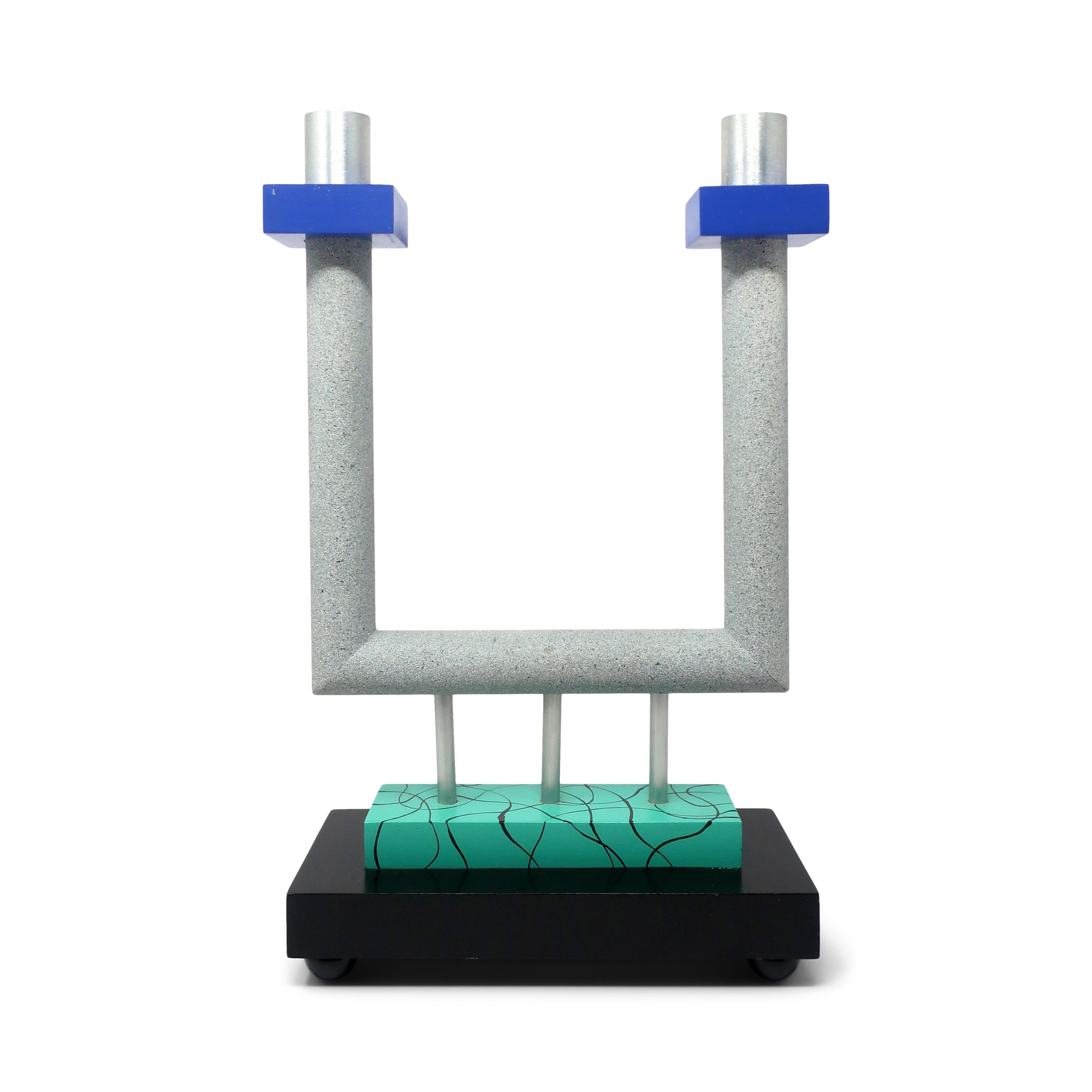 A stunning postmodern candlestick holder designed by Lyn Godley and Lloyd Schwan for their furniture, tabletop, and jewelry design company Godley-Schwan (1984-1998). Sitting on a black and turquoise base, the candelabra is constructed from lacquered