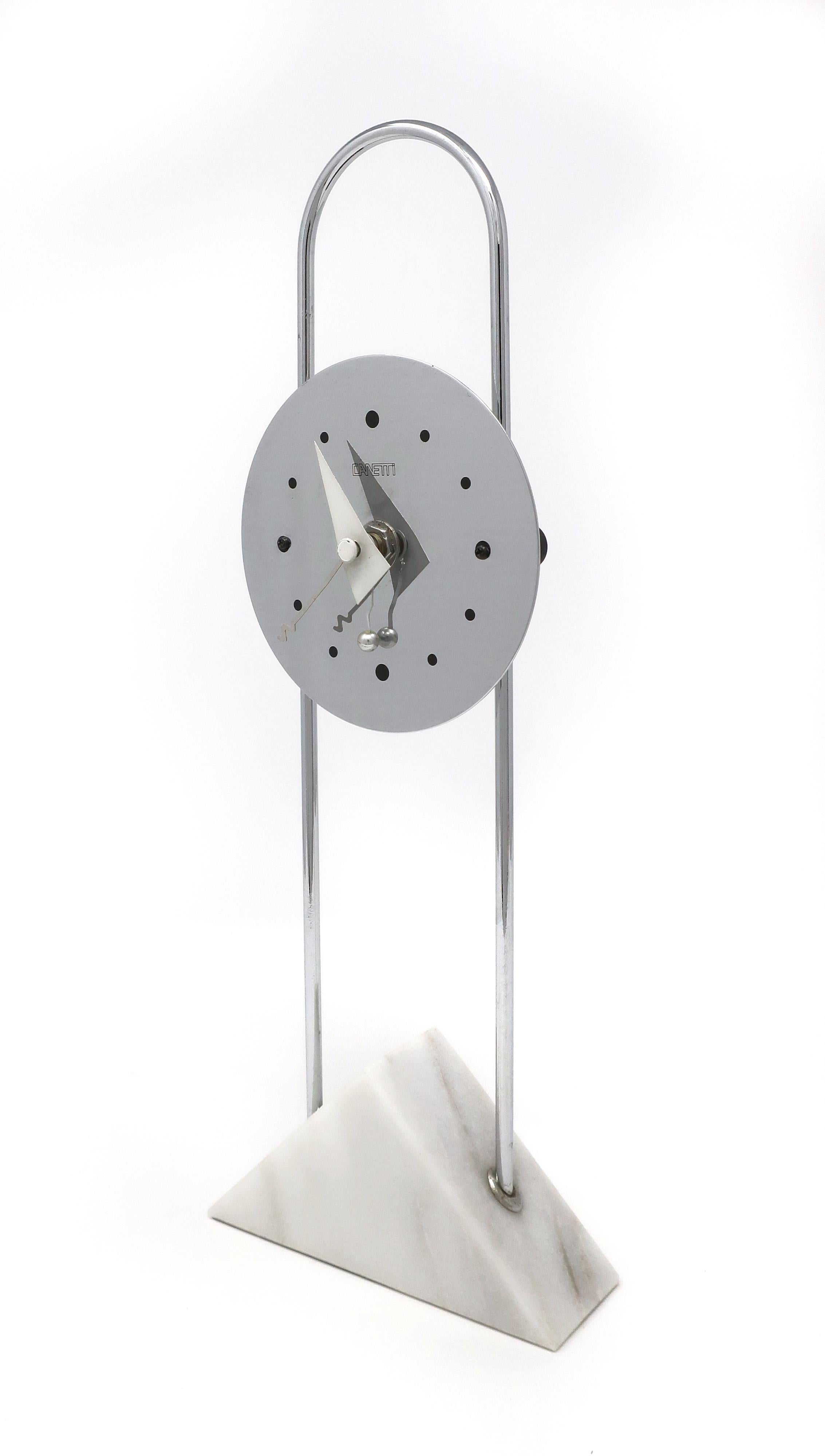 A stunning post modern clock by Canetti with a chrome face on an arching chrome stem set in a white marble base. Dated 1989, this clock screams its Memphis inspiration from the use of primary shapes to the quicky shapes of the clock’s hands. In very