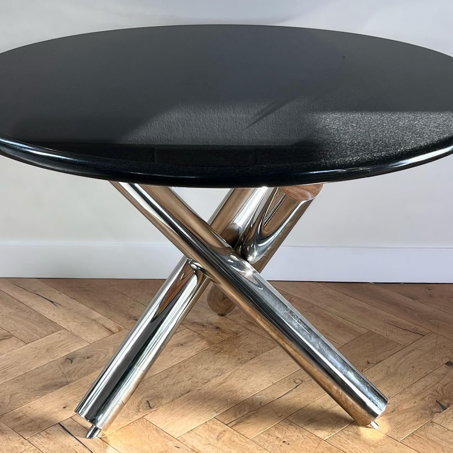 A postmodern circular dining - or entry - table, late 20th century. After J. Wade Beam for Brueton. Top is black granite; base is comprised of three crossed and fused chrome metal cylinders. Two pieces. Fabulous condition with little wear. Pick up