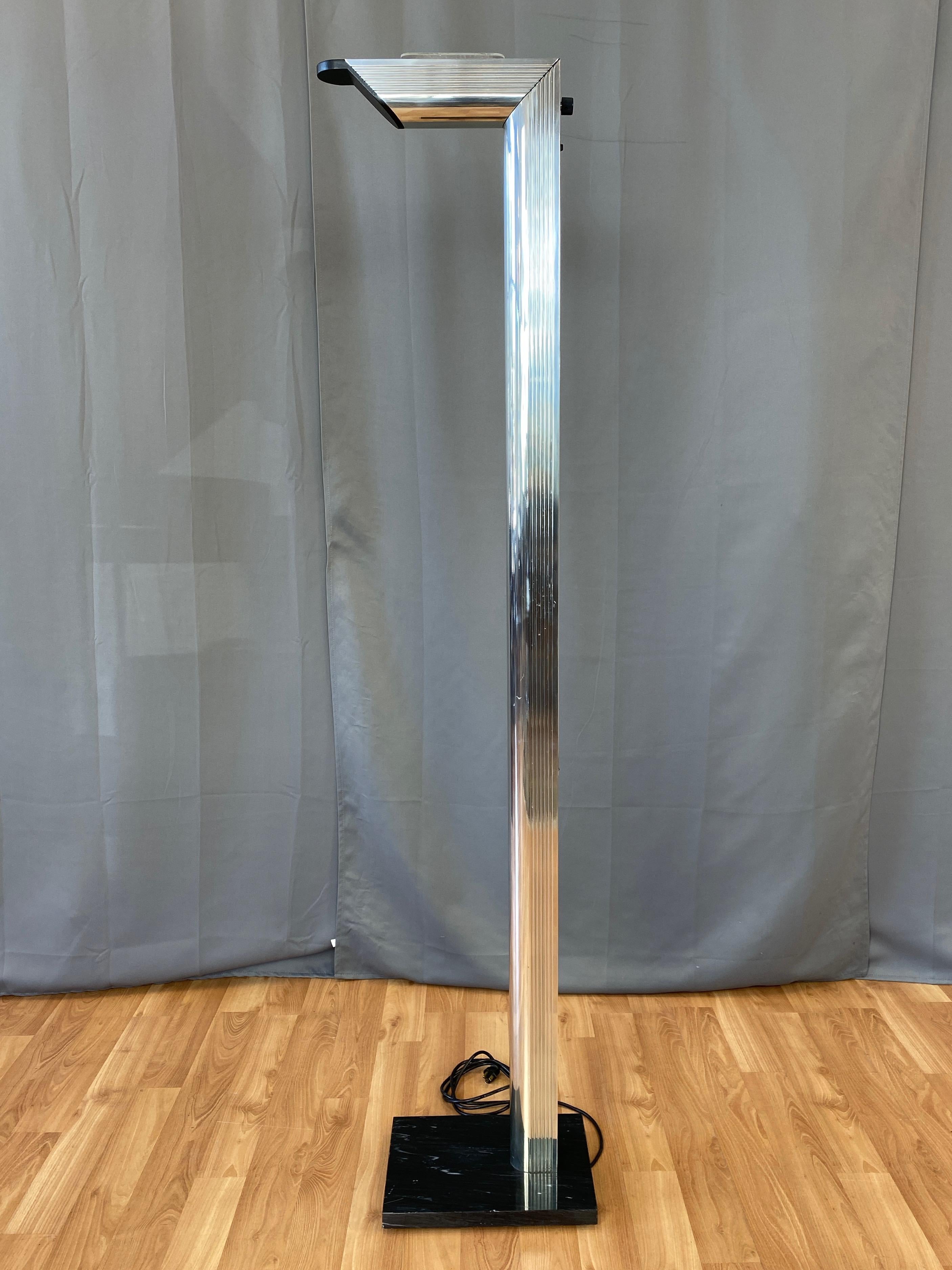 A very cool and uncommon 1980s postmodern chrome two-light torchiere floor lamp with black marble base.

Minimalist architectural aluminum body with chrome finish and black enameled trim stands tall like some futuristic periscope sentry. Features