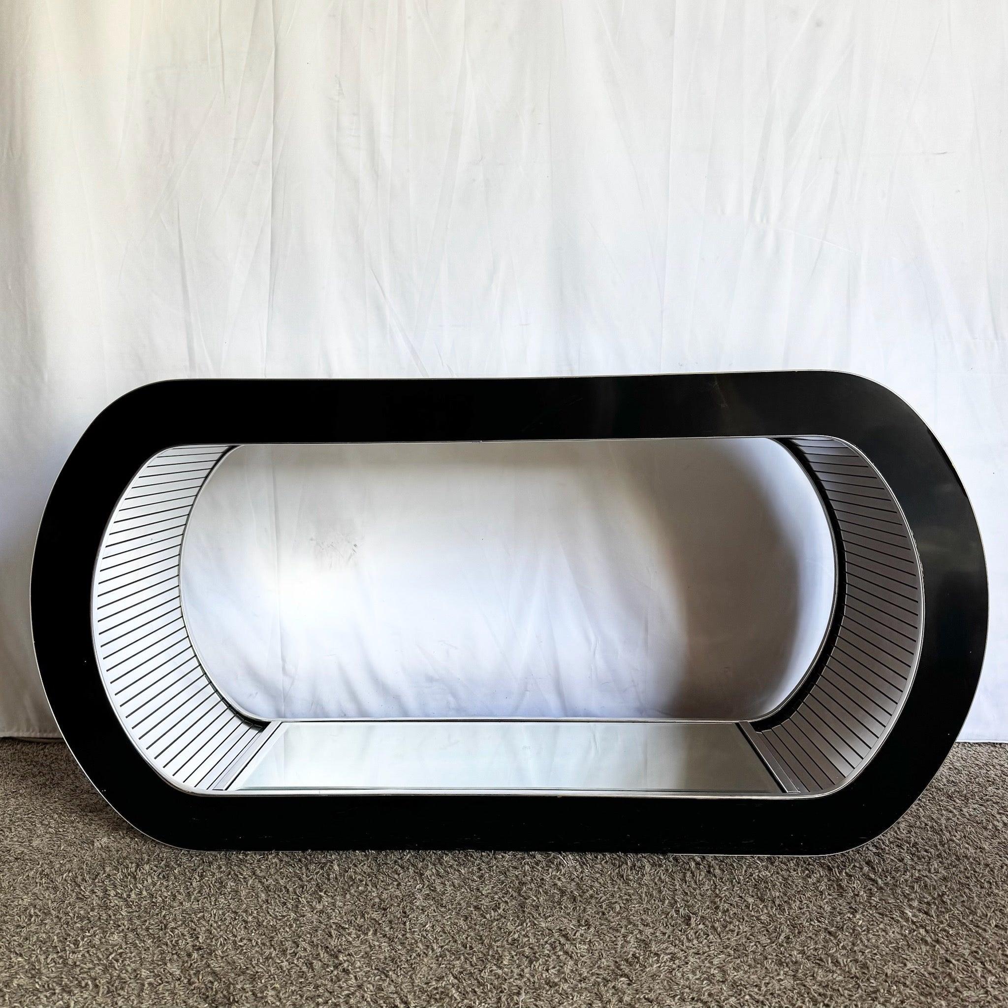 Elevate interiors with this Postmodern Chrome Mirror Waterfall Console—sleek black laminate, mirrored interior, glass shelf, and sculptural curves. 
 

 Some wear scratched and marks to the black and chrome as shown in the photos. Some pitting to