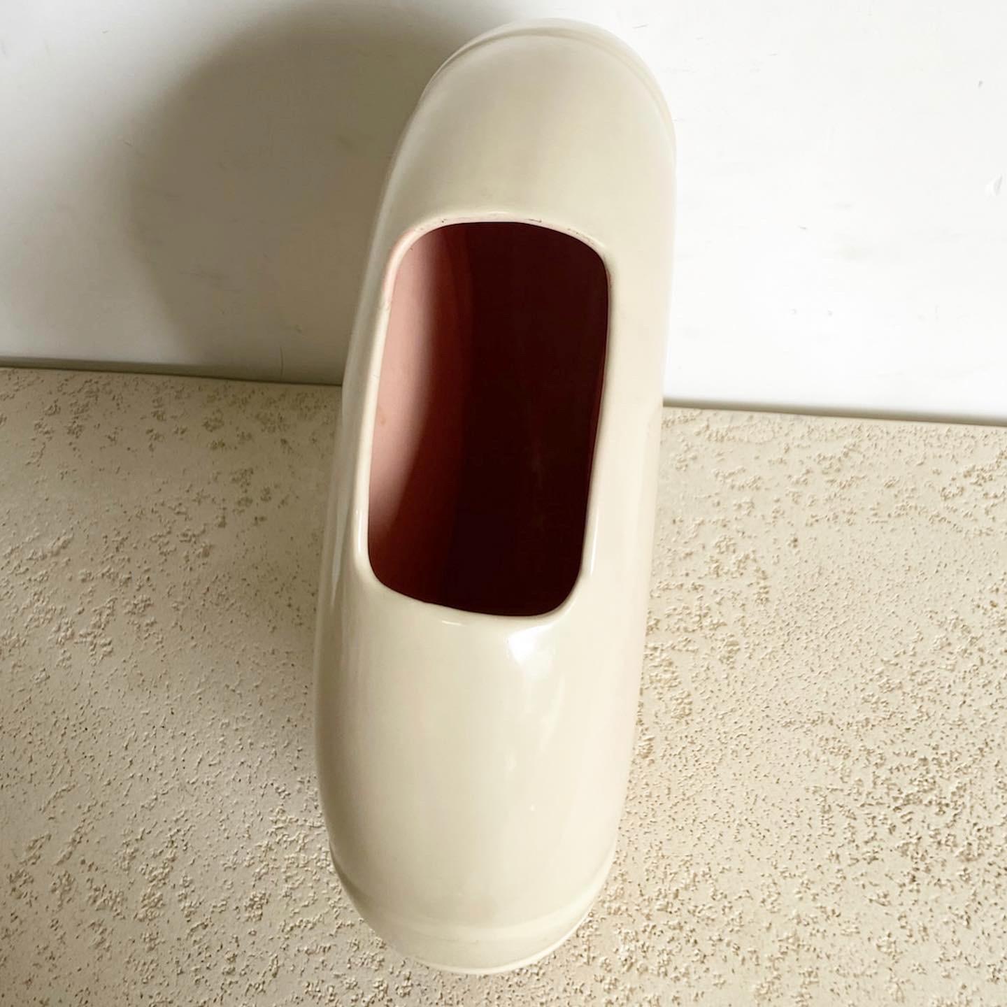 Voici le vase circulaire postmoderne de Haeger, une pièce élégante qui sert à la fois de vase fonctionnel et de sculpture autonome. Son design circulaire équilibré et sa teinte crème en font un complément polyvalent à tout style d'intérieur, du