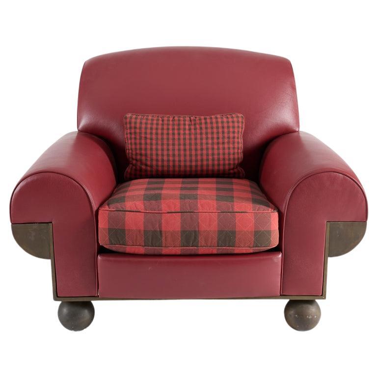 Ce fauteuil club postmoderne combine des formes, des matériaux et des détails improbables. Le poids important repose sur deux sphères au lieu des pieds, et les accoudoirs surchargés et très arrondis, revêtus de cuir rouge, s'étendent jusqu'à de