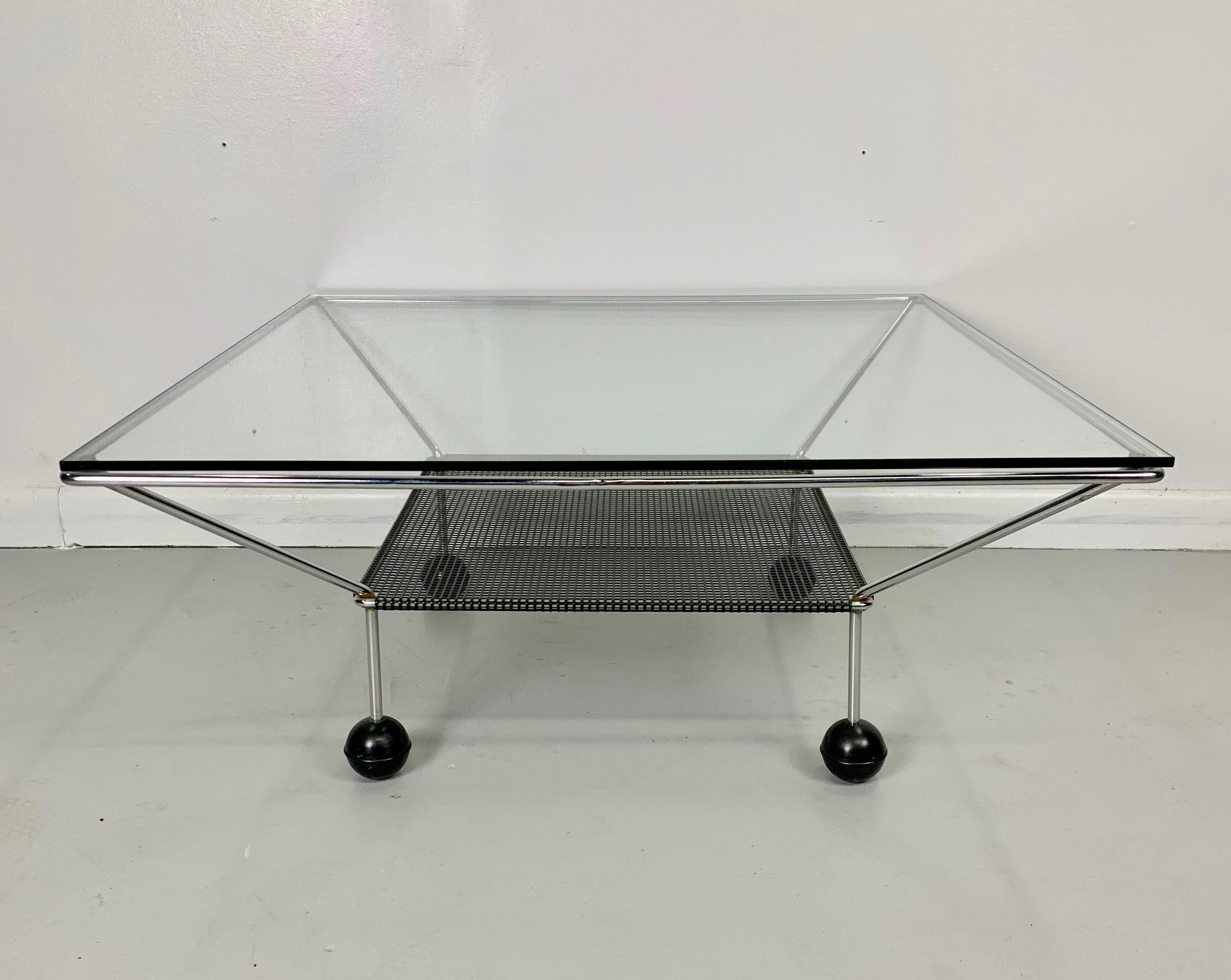 Unique table consisting of a chrome frame sitting on black ball feet with a perforated metal shelf.
This table was produced in the era of the Postmodernists such as Sottsass, de Lucchi, Graves, Shire and others.
