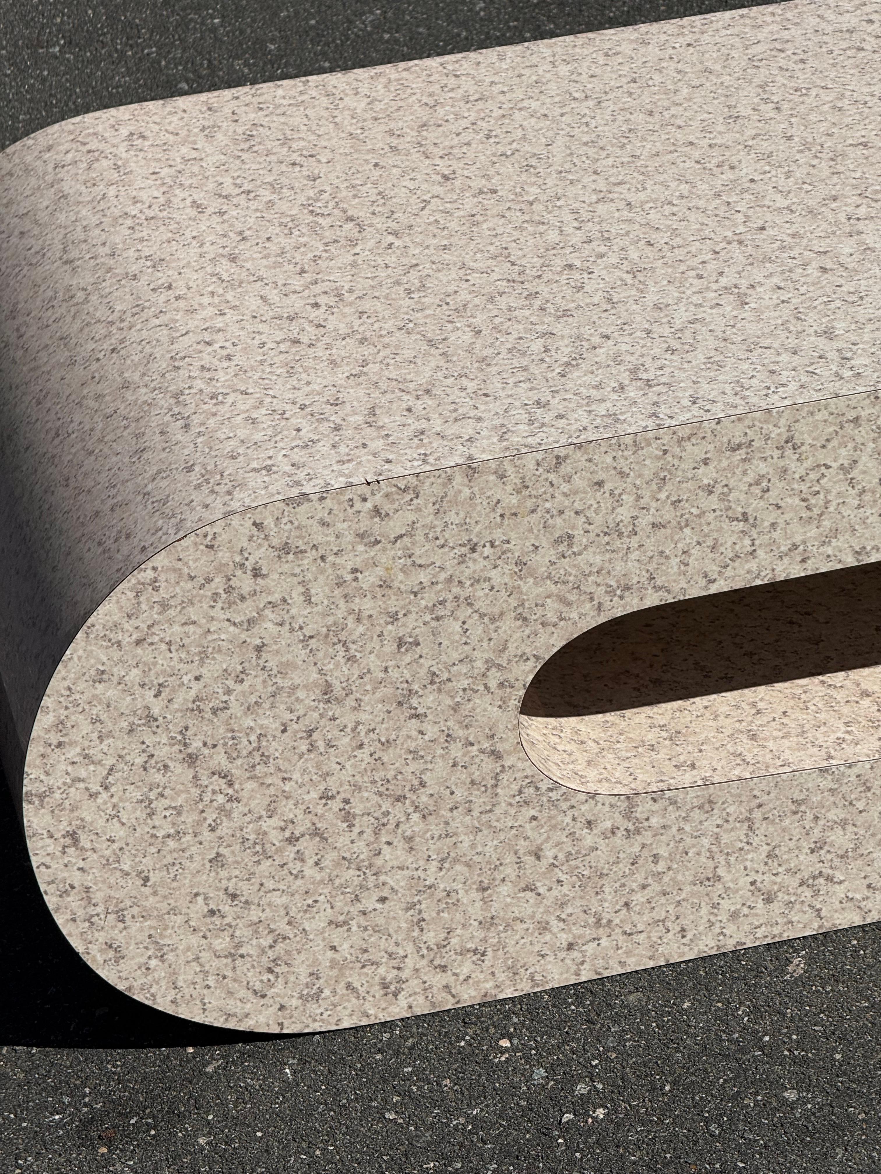 Tavolino postmoderno in finta pietra alla maniera di Pierre Cardin. Questo pezzo è piuttosto grande e ha una forma a sbalzo unica. Il piano e i lati in laminato di finto granito rendono il pezzo estremamente resistente. Il colore neutro permette di