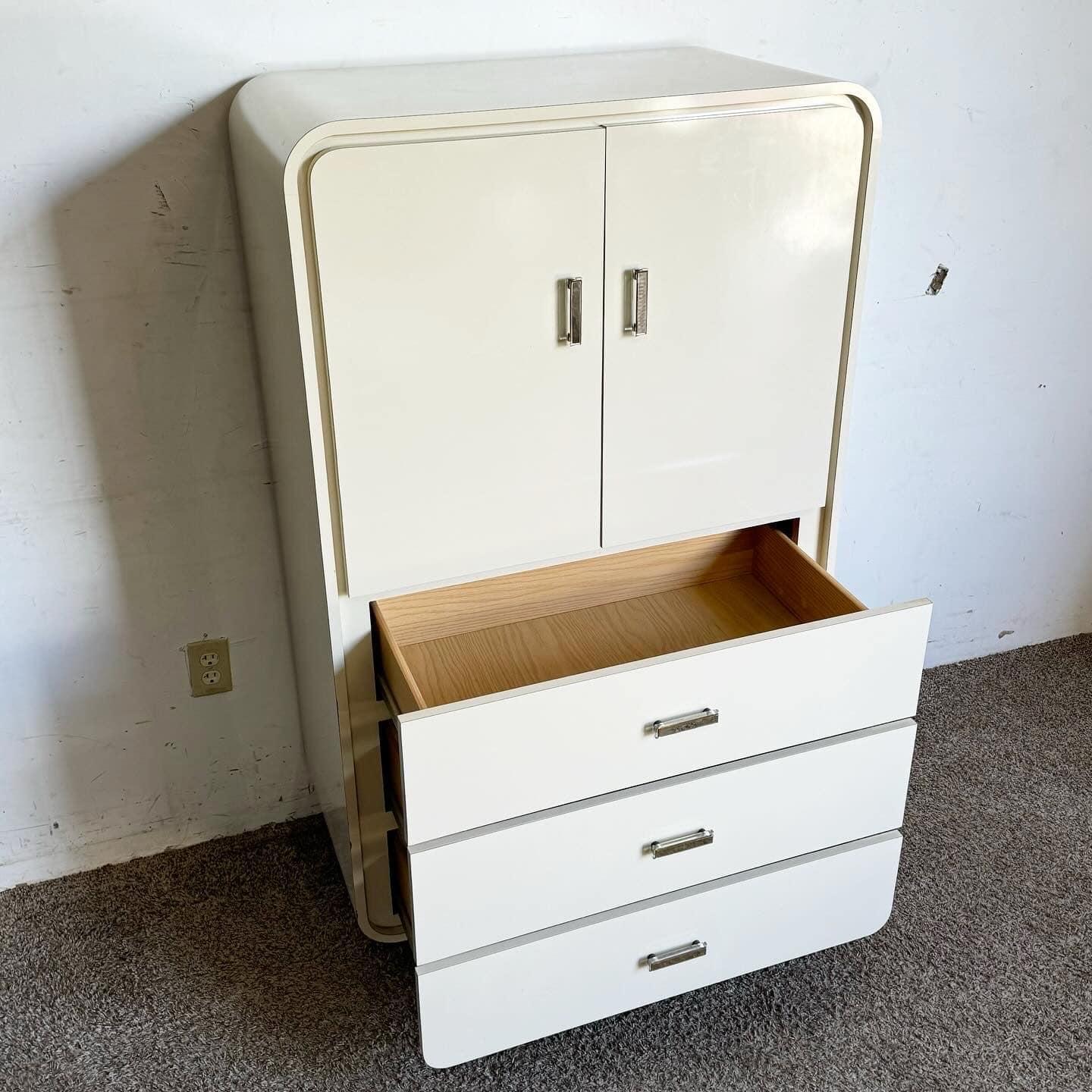 This elegant Postmodern Cream Lacquer Armoire is a chic and functional addition to any bedroom. Featuring a sleek, curved design, it offers ample storage with three spacious drawers and a cabinet with adjustable shelves. The glossy cream finish and