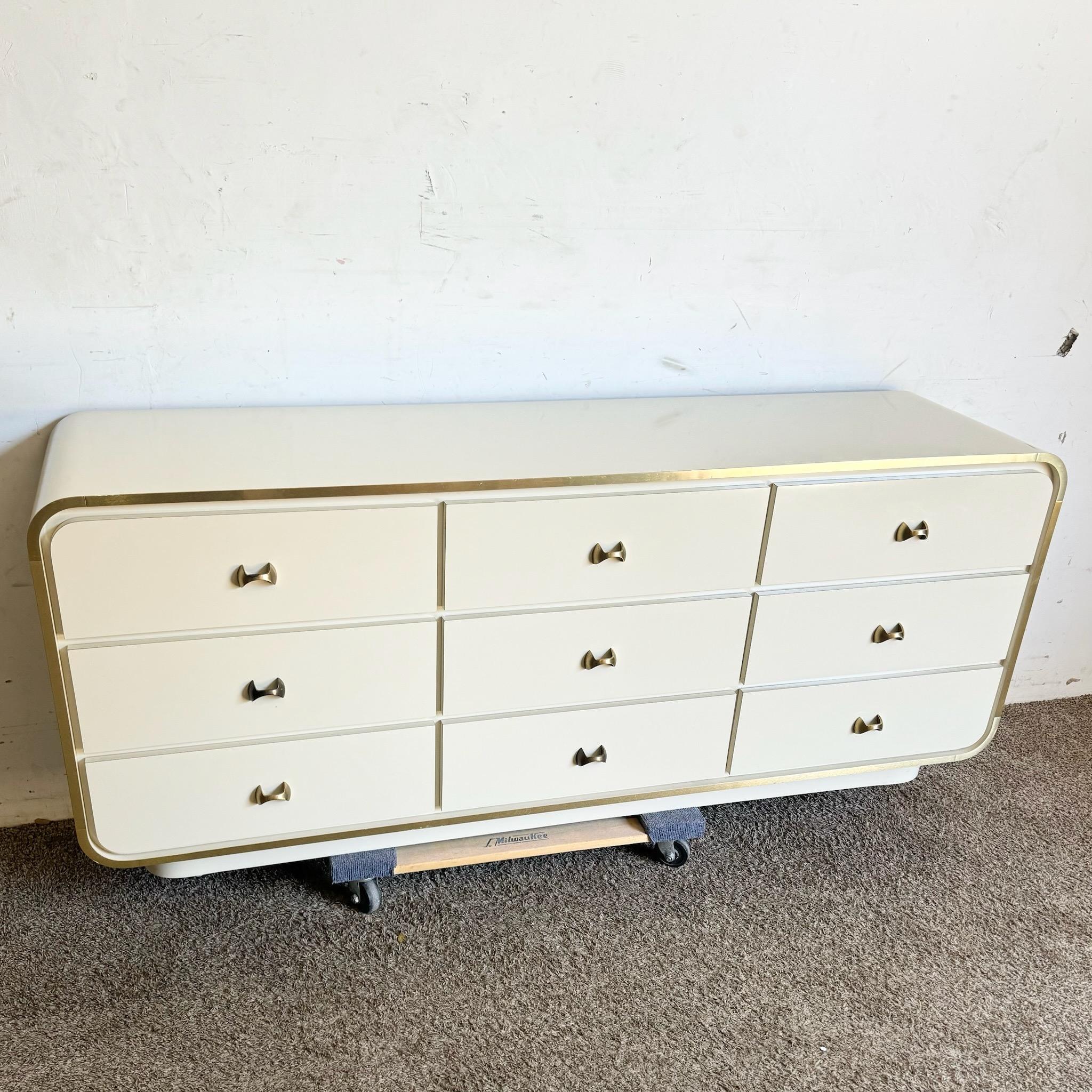 Make a statement with this postmodern cream lacquer laminate waterfall dresser, featuring elegant gold accents. The sleek waterfall design combined with the glossy cream finish creates a sophisticated and modern look, while the gold accents add a