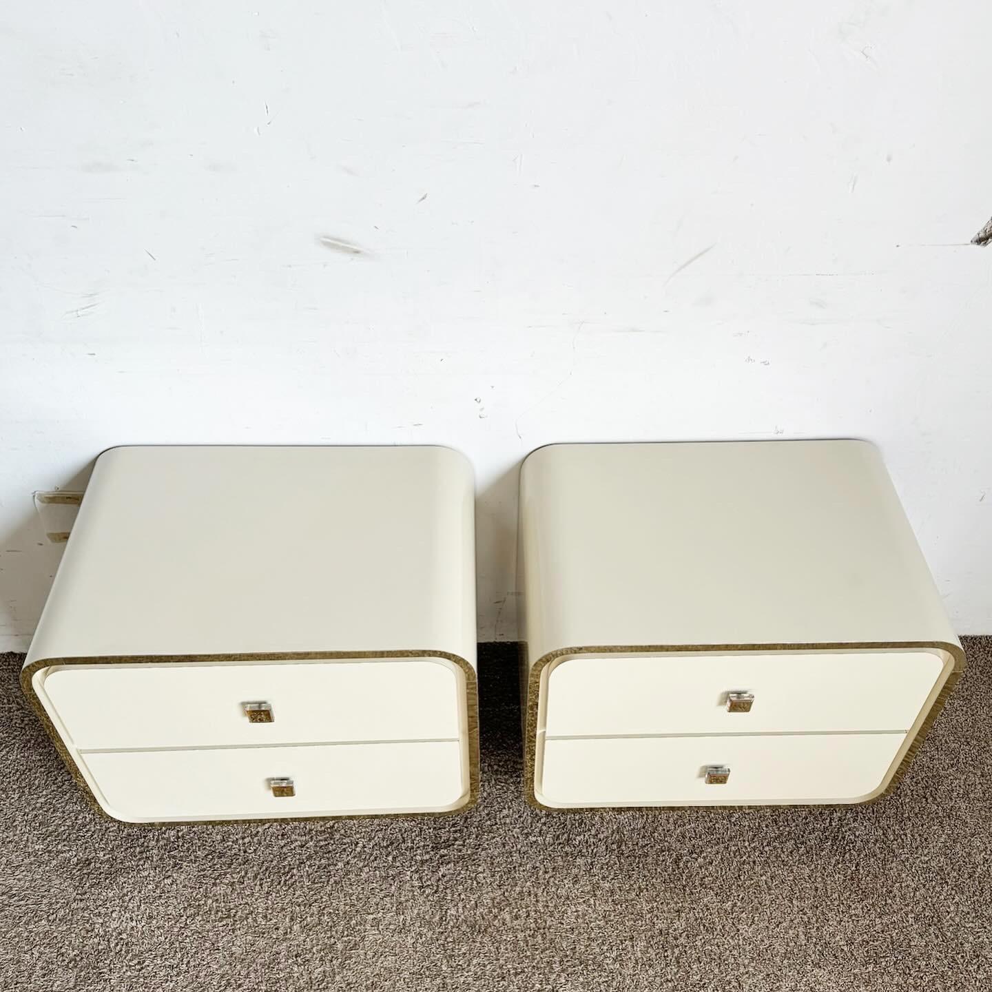 Elevate your bedroom with the Postmodern Cream Lacquer Laminate Waterfall Nightstands with Gold Trim. These nightstands boast a sculpted waterfall design in a cream lacquer finish, accented with elegant gold trim. Offering practical storage with
