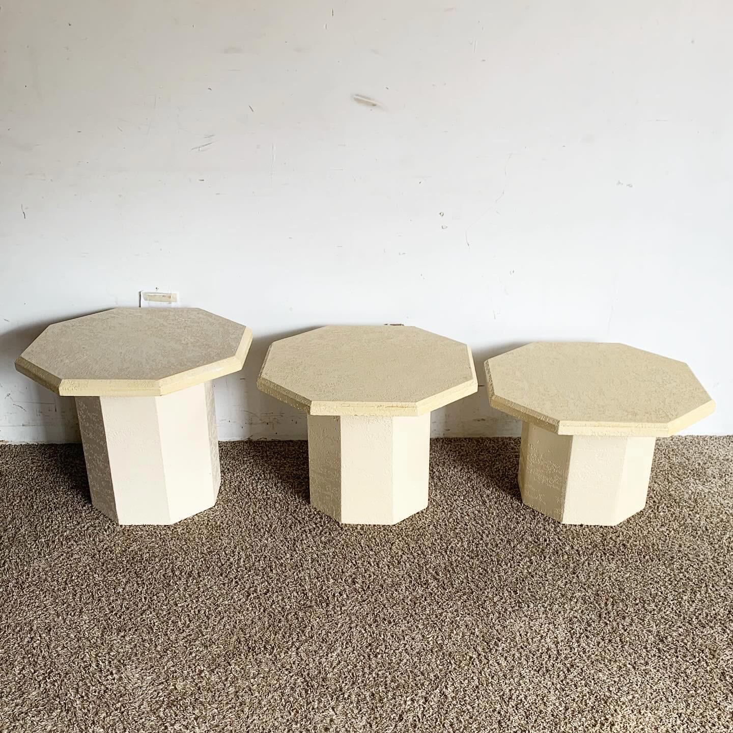 Elevate your interior with a set of three Postmodern Cream Octagonal Faux Stone Nesting Tables, showcasing versatile functionality and a unique aesthetic with octagonal tops and curved bases, perfect for adding sculptural elegance to modern