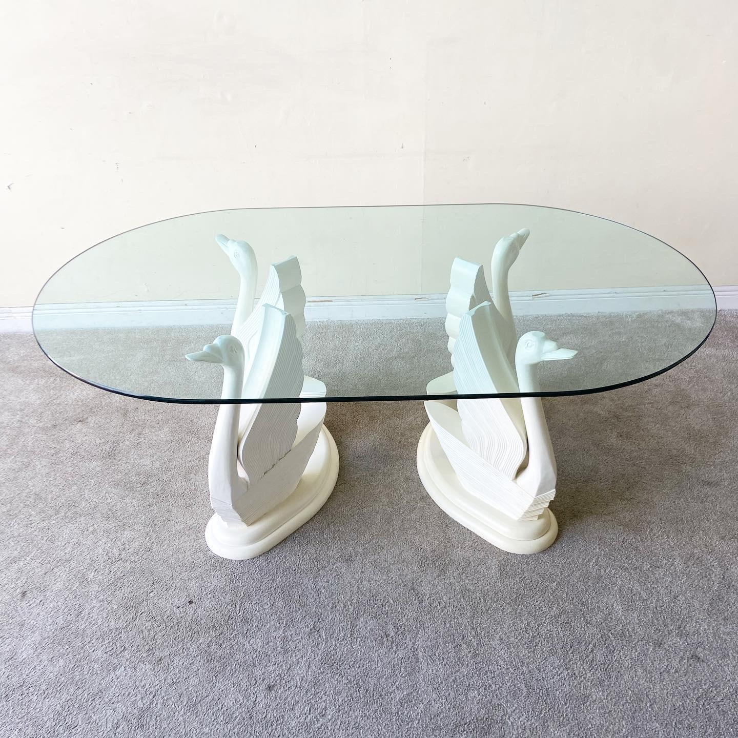 Stunning 1980s oval glass top dining table. Glass rests on two identical pedestals, each of which are comprised to a pair of swans.