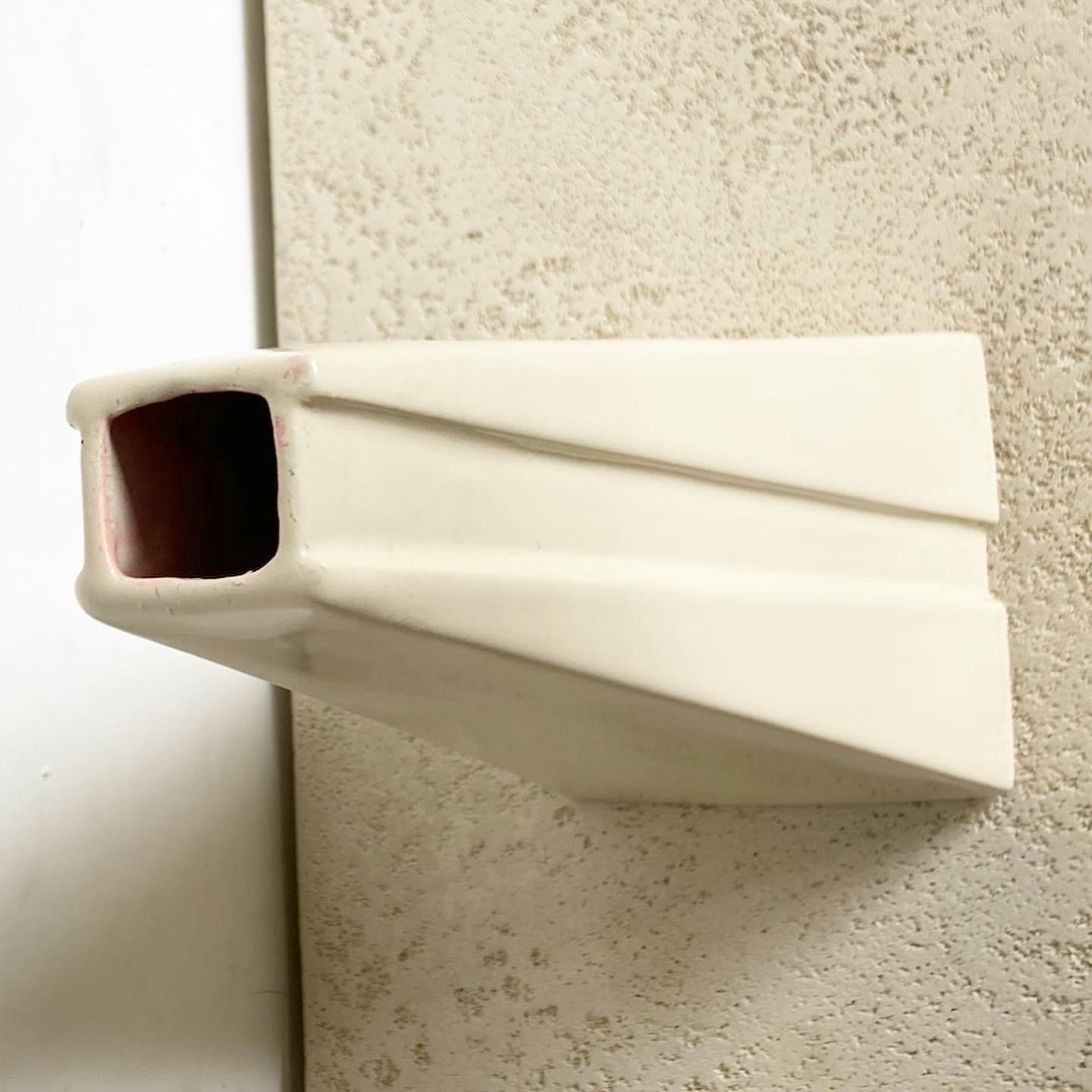 Voici le vase pyramidal Postmodern Cream de Haeger, un mélange unique de design géométrique et de tons neutres et doux. Non seulement il sert de vase fonctionnel pour les arrangements floraux, mais sa forme pyramidale en fait également une œuvre