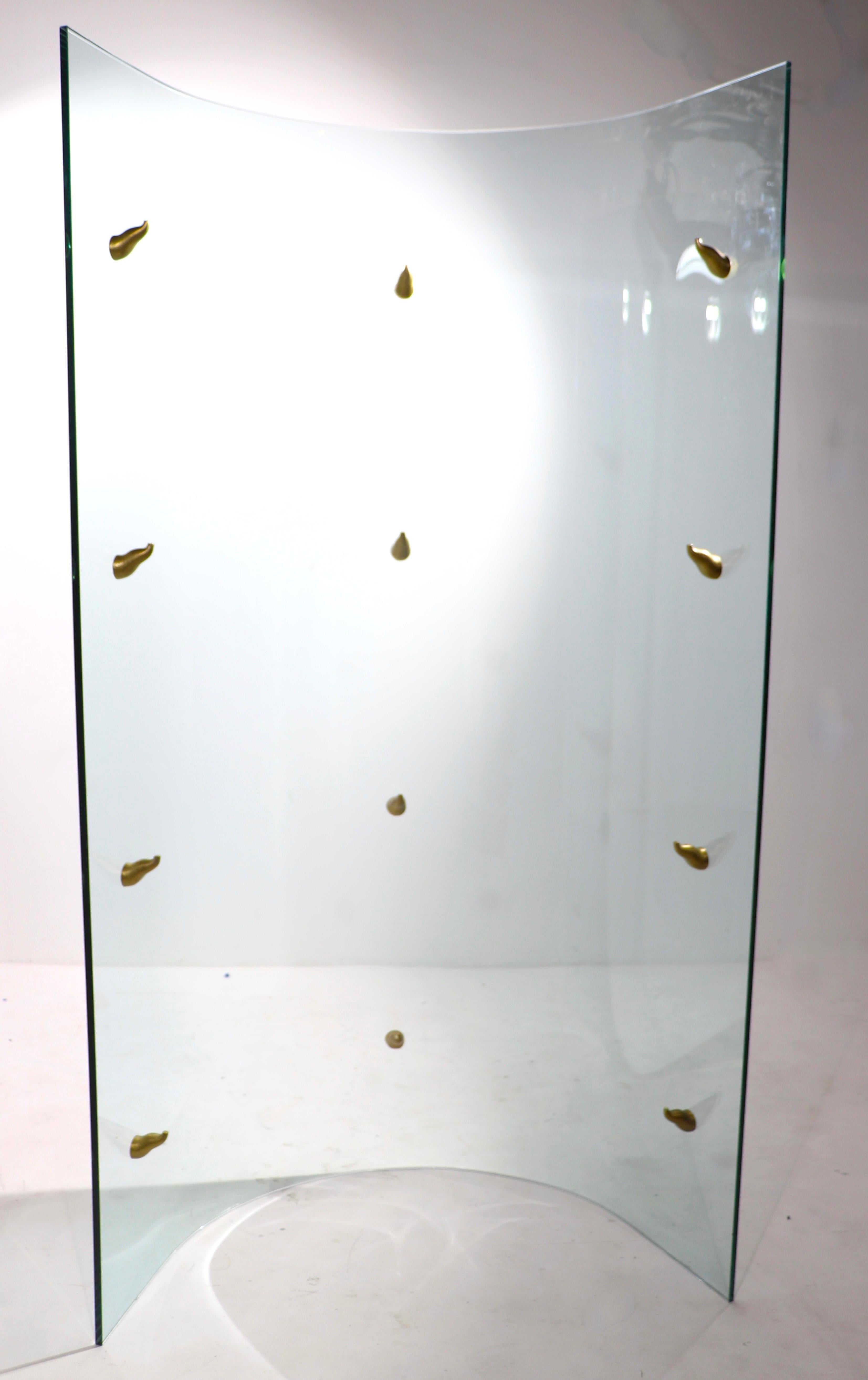 Spectacular glass display shelf having a curved glass body, with 4 glass shelves, each rests on unusual organic formed cast brass supports. The piece is in amazing, undamaged, original condition. We believe it is a Philippe Starck design, however it