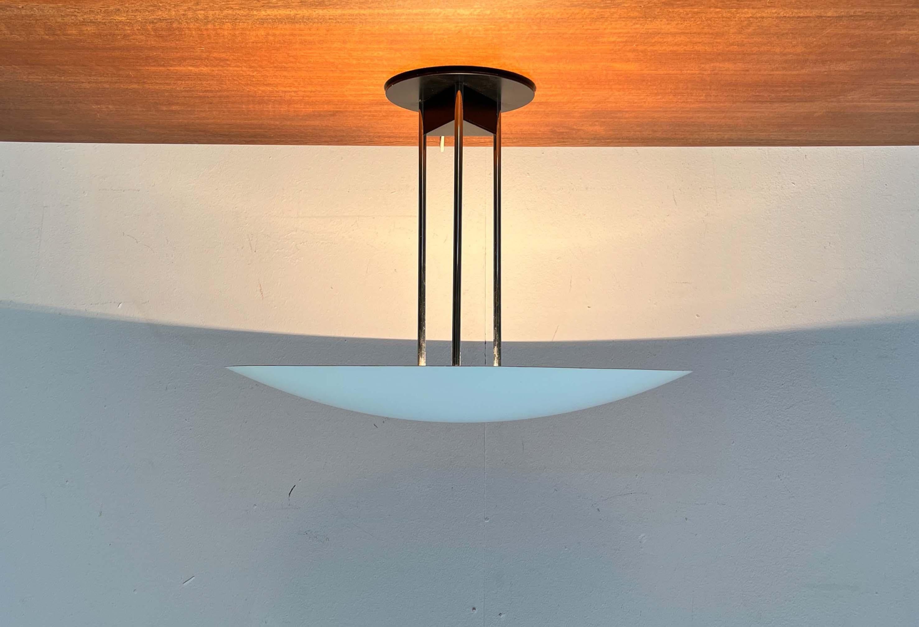 Elegant ceiling light from Danish manufacturer Nordisk Solar, designed by Hans-Agne Jakobsson. 

The light consists of flat shells that act as reflectors and an intricately designed shaft with a base. The large shell covers the light source and