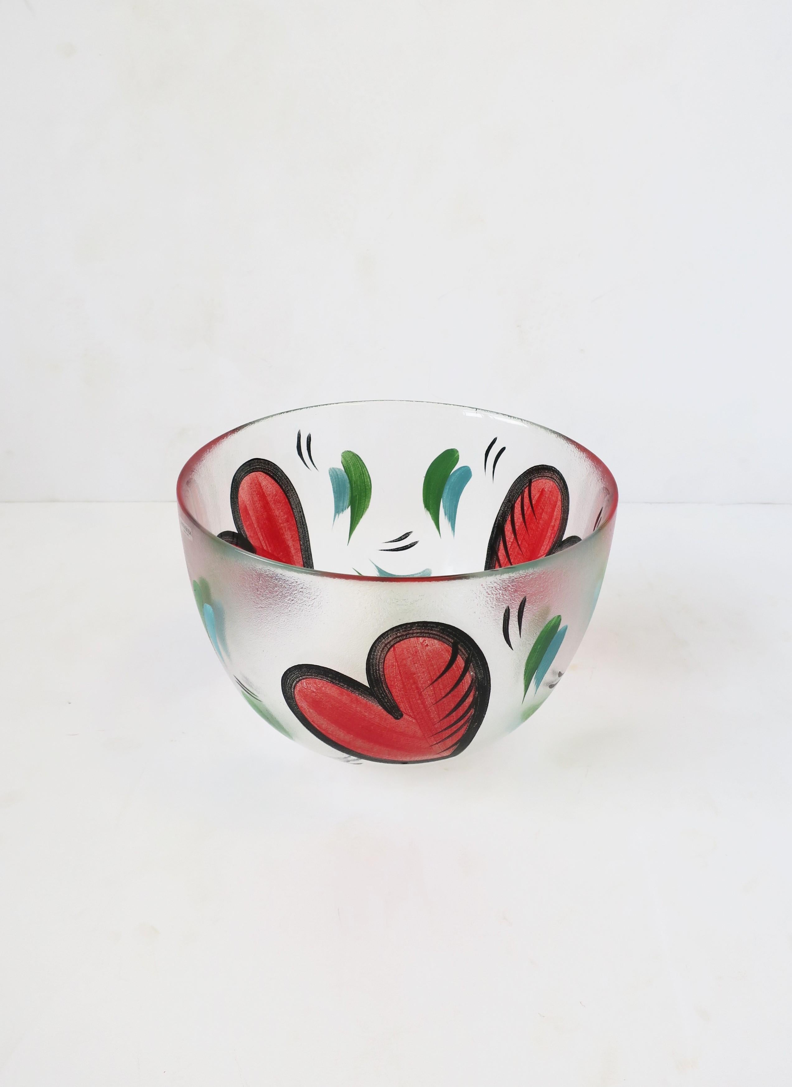 A fun and beautiful Postmodern Swedish bowl, hand painted with big red hearts, signed by Artist, Ulrica Hydman-Vallien, for Kosta Boda, Sweden, late 20th century. Artist/designer: Ulrica Hydman-Vallien (b. 1938-d. 2018.) In addition to being a great