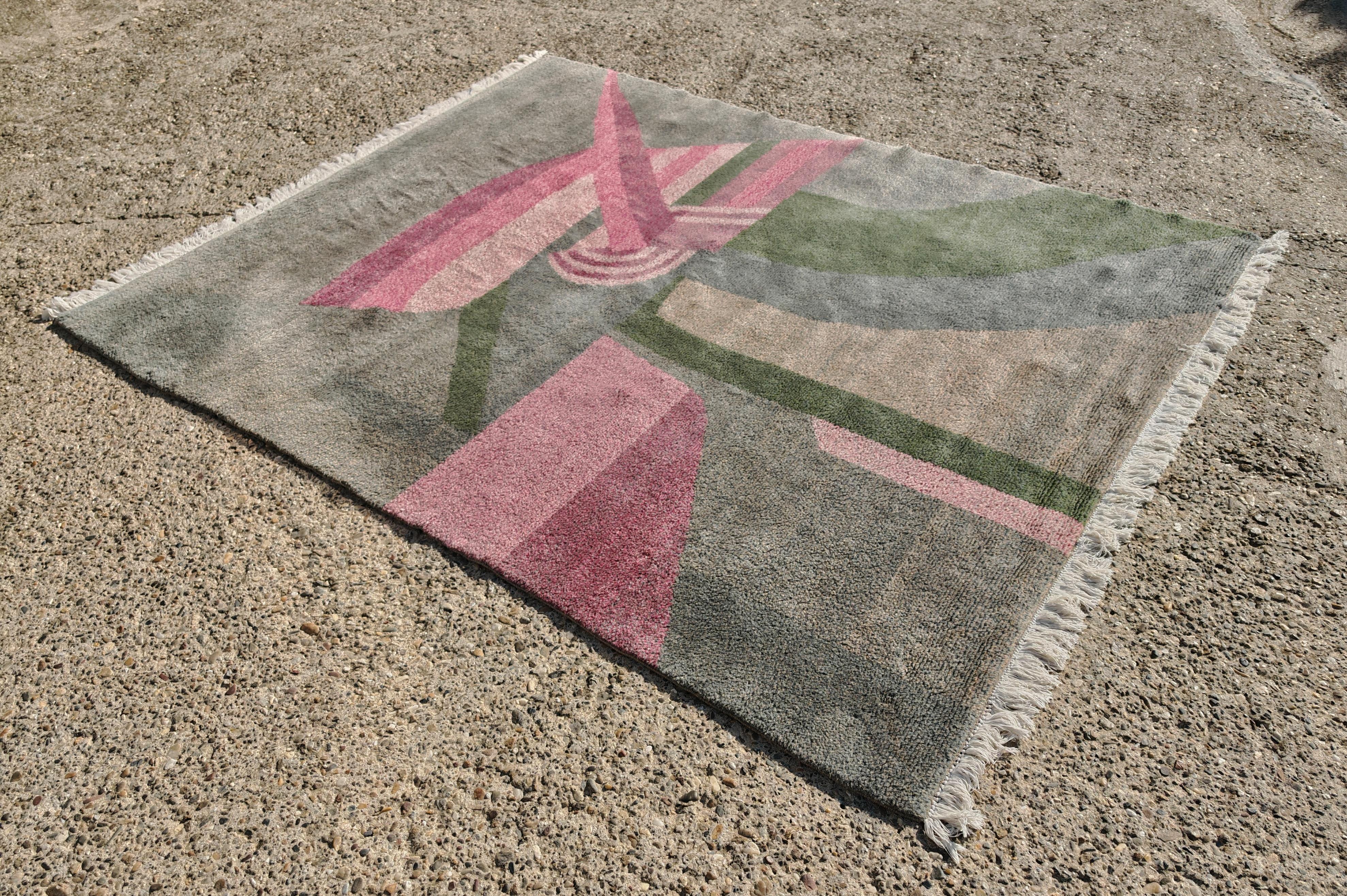 In questa inserzione troverai uno splendido tappeto postmoderno con motivo astratto. Presenta una bellissima tavolozza di colori, dal grigio medio scuro a diverse sfumature di rosa e verde polveroso. Il tappeto è stato realizzato a mano con 100€ di
