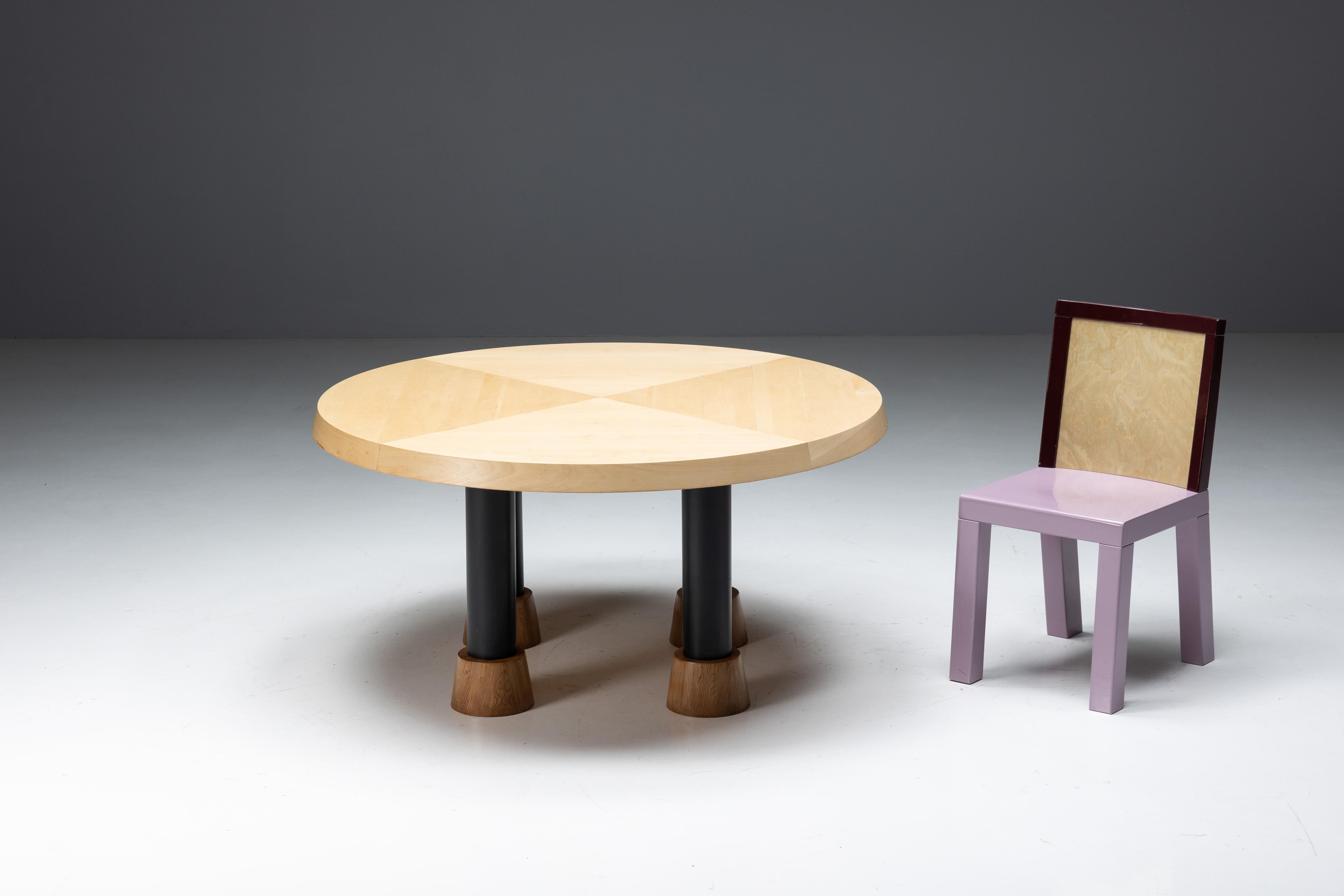Table de salle à manger ronde conçue par Ettore Sottsass, une pièce de design postmoderne dans le style Memphis. Le plateau rond en bois massif est soutenu par quatre pieds en métal avec des bases en bois. Cette table trouve un équilibre harmonieux