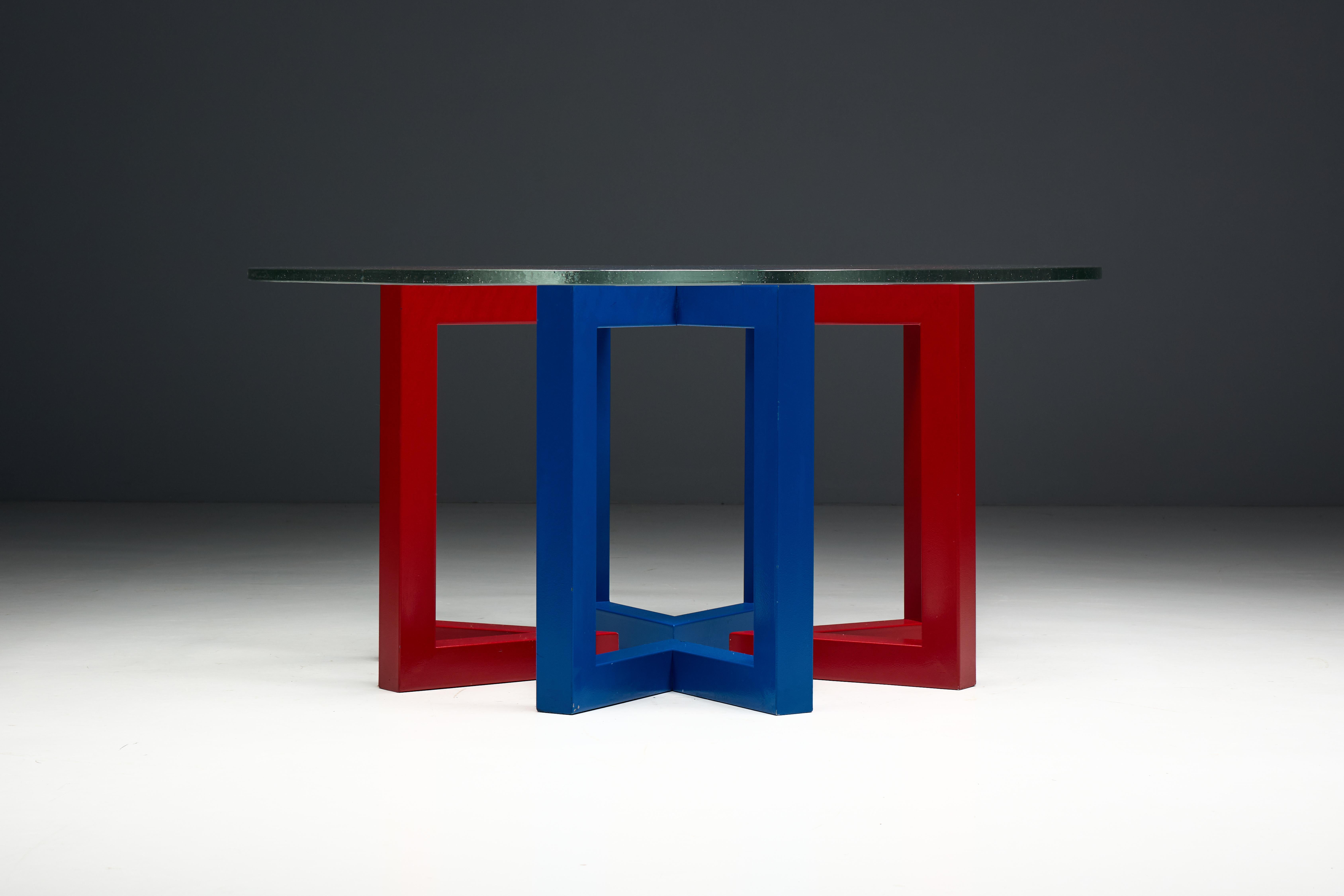 Questo sorprendente tavolino da caffè postmoderno è definito dalla sua audace base scultorea e dalla vivace tavolozza di colori primari. La struttura geometrica - composta da un intreccio di metallo laccato rosso e blu - crea una presenza