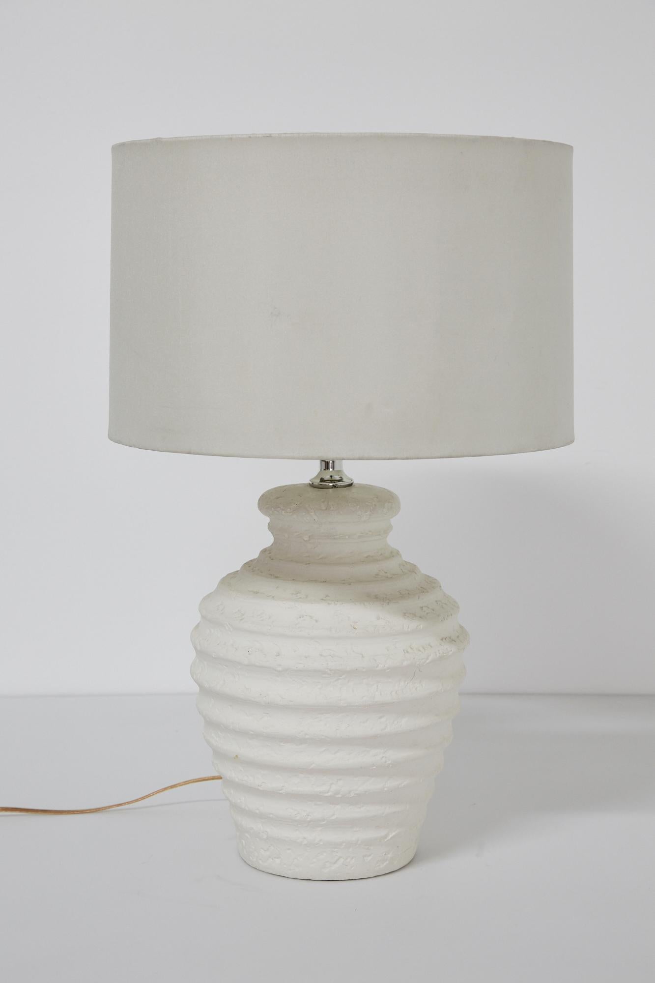 Urn-shaped distressed plaster table lamp with horizontal ribbing. Chrome neck. Signed to back of lamp with Elite '93.

Body only measures 13.5
