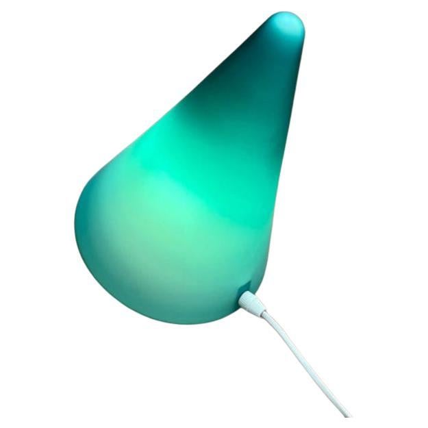 Simple cone table lamp made of glass from Mobo Light from the Netherlands.

The cone-shaped diffuser is made entirely of glass. The glass is overlaid green. The cable exits visibly from the back of the cone. This piece has an attribution mark,
I am