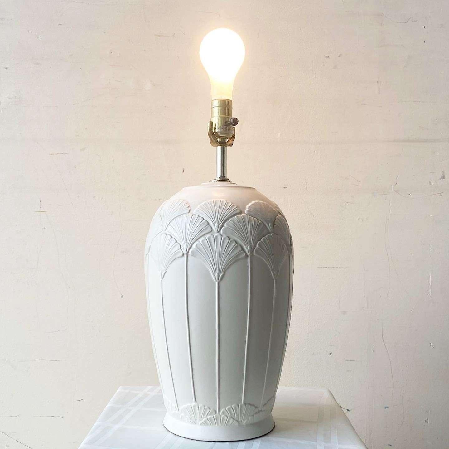 Étonnante lampe de table vintage postmoderne en céramique. Les fleurs gravées entourent le corps de la lampe en finition beige.
