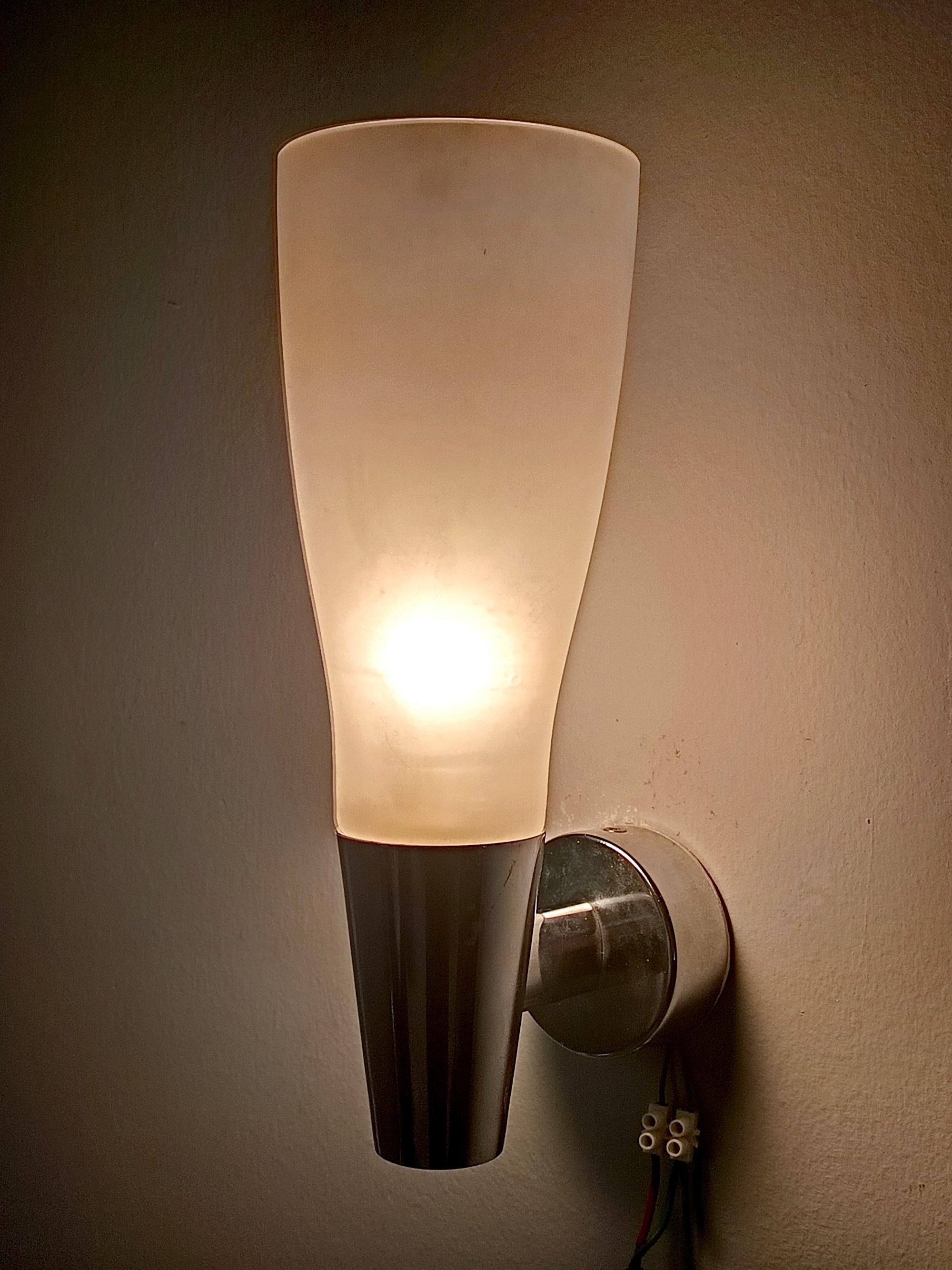 This sconce was manufactured by Fontana Arte in Italy in 1970s based on a Pietro Chiesa's design of the 40s. 
It has a chrome-plated metal frame and an etched glass shade. 
In addition to this, it features its original label.
It is vintage,