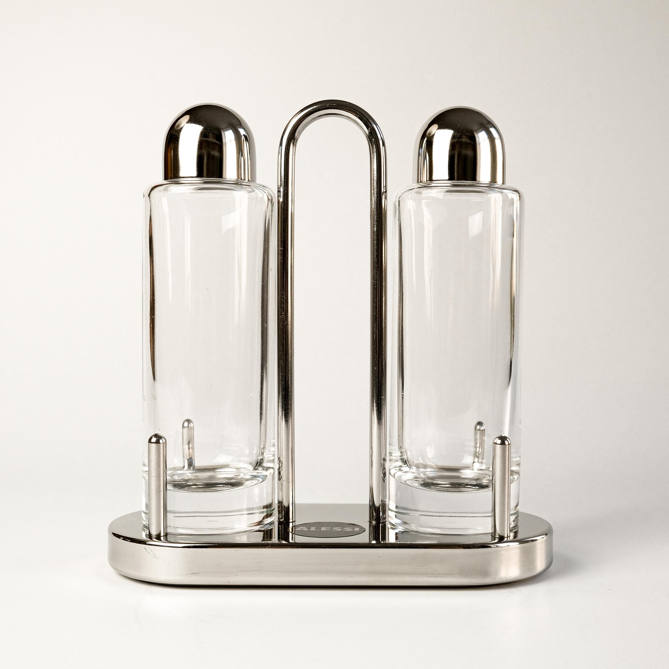 For sale is the iconic Postmodern 'Model 5074' Oil & Vinegar set, designed by Ettore Sottsass and produced by Alessi, Italy in 1978 (this is a more recent edition).

Released in the late 1970s, this piece embodies the vibrant spirit of Italian