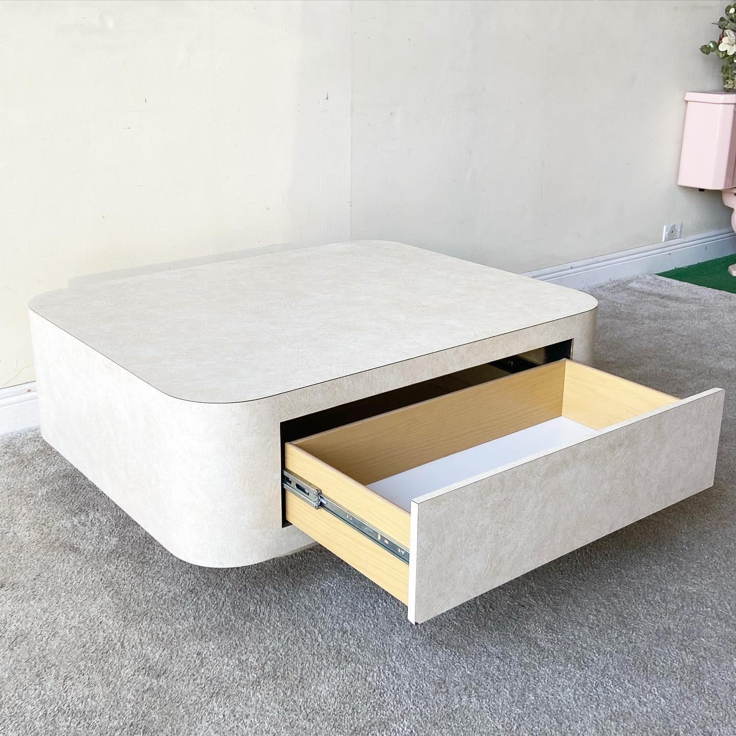 Incredible postmodern square coffee table with two spacious drawers. The table features a faux goat skin vinyl laminate giving it a unique surface texture.

Additional Information:
Material: Vinyl, Wood
Color: Cream
Style: Postmodern
Time Period:
