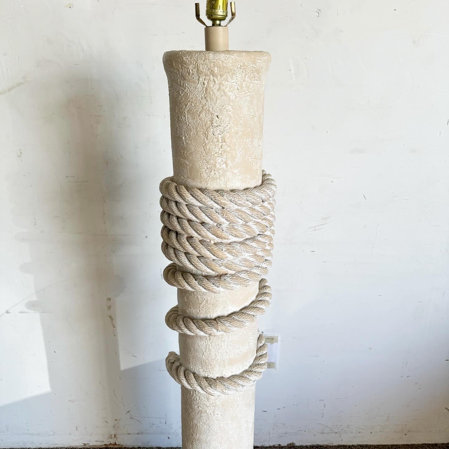 The Postmodern Faux Roped Pillar Floor Lamp is a unique and elegant addition to any room. With an off-white/beige textured finish, it exudes contemporary sophistication. The highlight is its sculpted faux rope detail, adding artistic flair. This