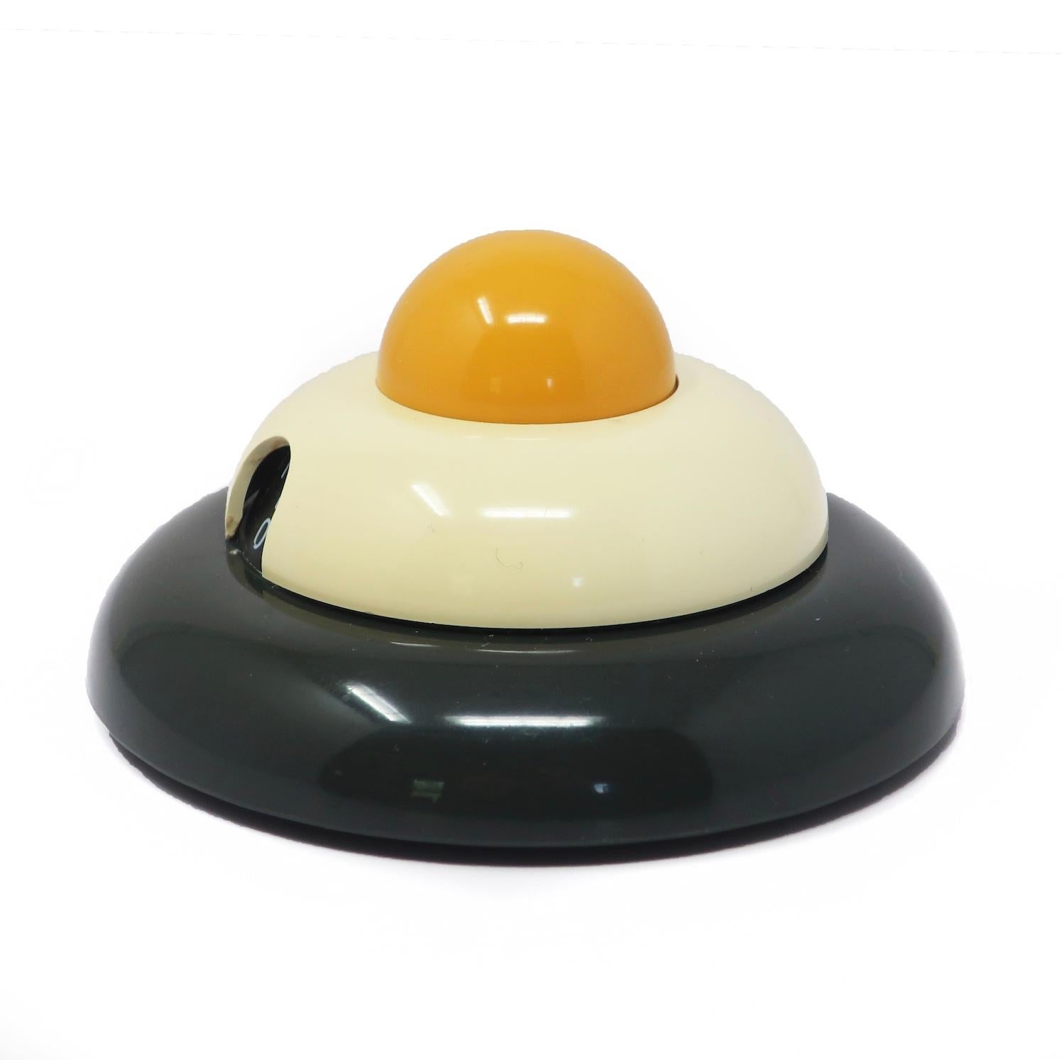A whimsical Italian postmodern multicolor kitchen timer designed by Roberto Pezzetta for WikiDue.  Stacked dark gray, white and yellow discs give it a fun Memphis Milano-inspried take on an egg in a pan.  Runs for up to 60 minutes.

In very good
