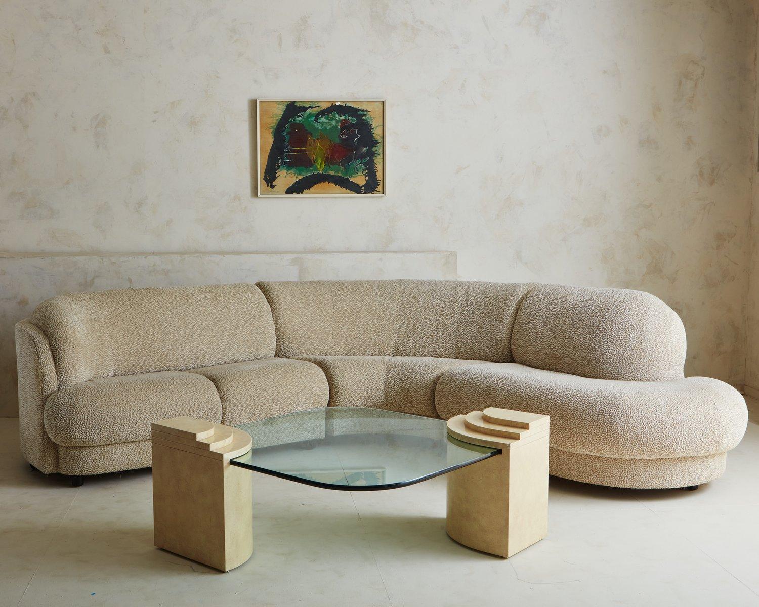 A vintage coffee table featuring a 1” thick square glass table top with rounded edges. The top fits into two cream faux marble laminate supports on opposite ends. Each support has three decorative curved tiers. USA, 1990s.