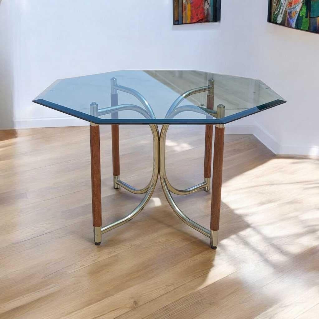 Une table de salle à manger distinctive dans la tradition postmoderne des années 1980, fabriquée avec un plateau en verre octogonal biseauté et une base sculpturale composée de chrome plaqué laiton et de bois de chêne massif. Cette pièce remarquable