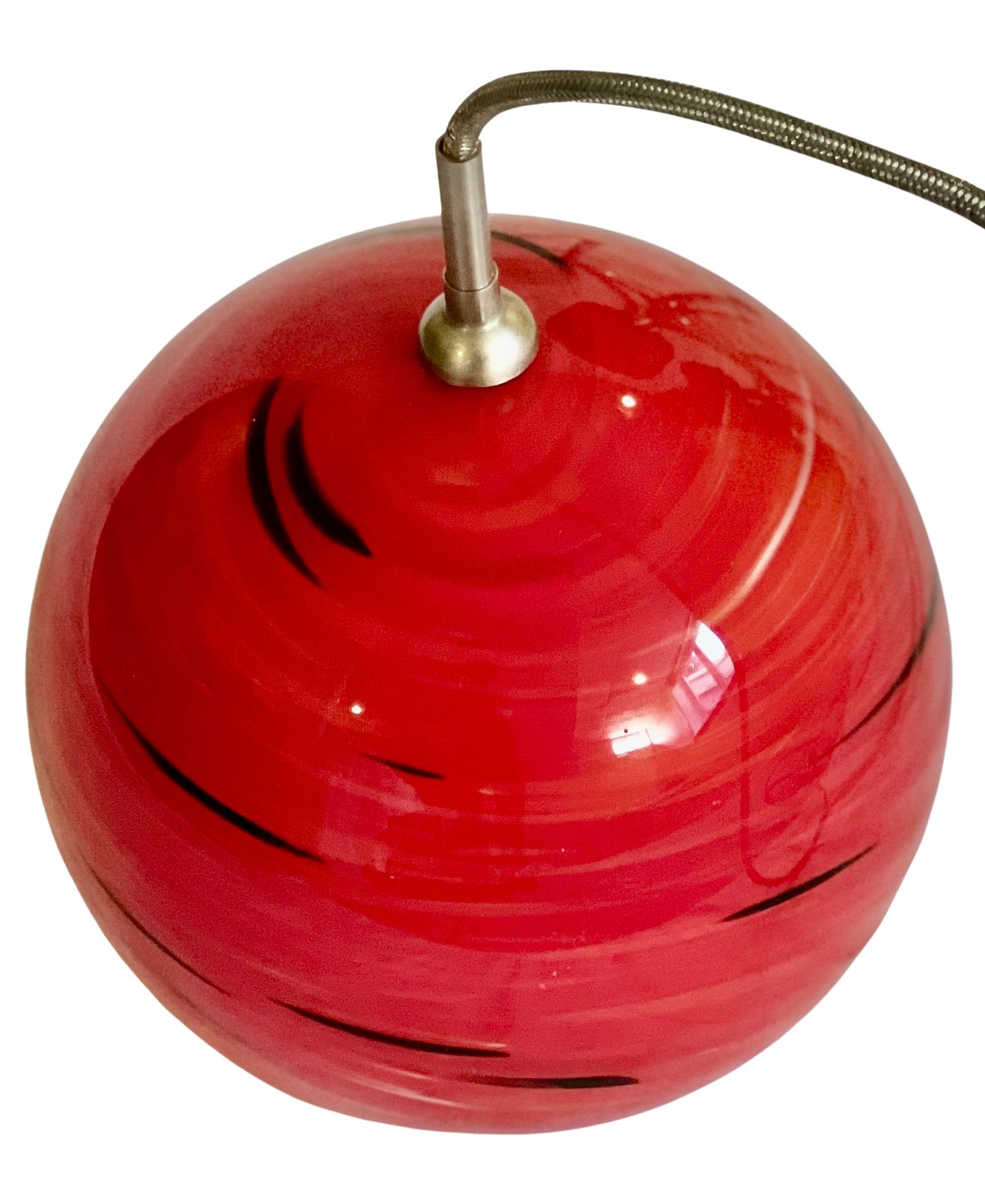 Postmodern single glass globe pendant. 

Red globe with swirls of black and white. Long cord attached is 100 inches.