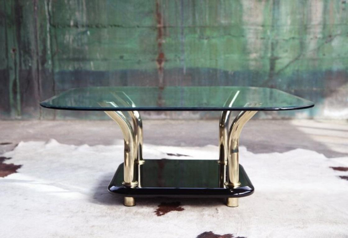 This minimalist, post modern Miami Regency 1980's coffee / cocktail table .  This piece would look great in a Modern or Mid-Century decor. It features classic chic sculptural lucite brass finished structure with a beautiful black lucite base. The