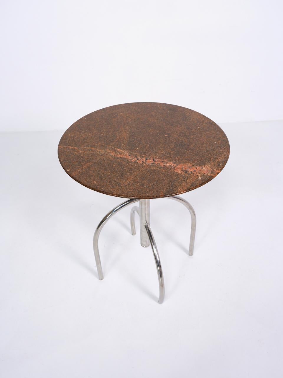 A late 20th century side table composed from a sculptural chrome plated tubular steel frame and granite top. 

Dimensions (cm, approx):
height: 61
diameter: 50.
 