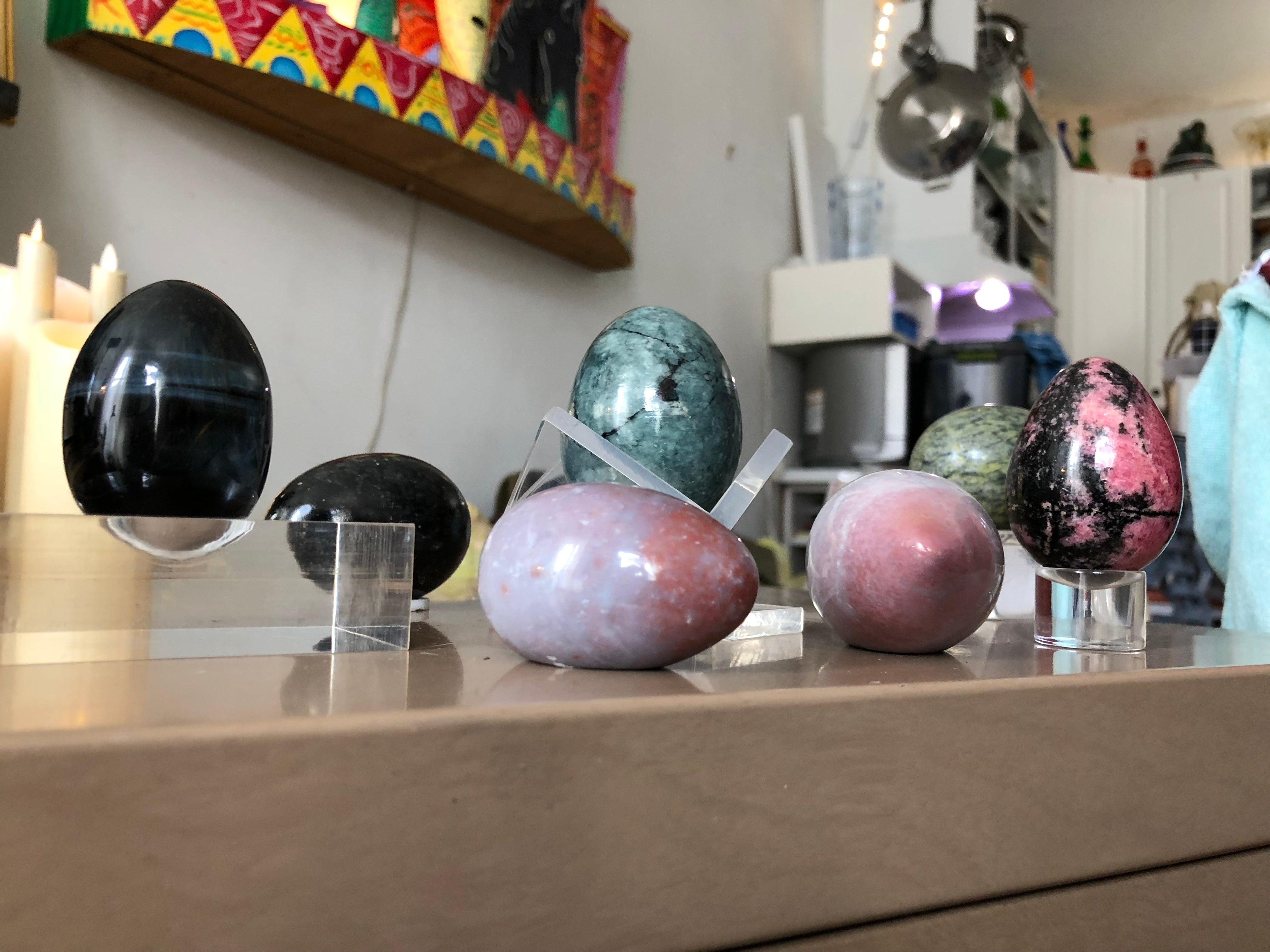 Ensemble soigneusement sélectionné d'œufs en pierre semi-précieuse et en verre dans des couleurs vibrantes, avec des bases de plate-forme en Lucite correspondantes pour la présentation. L'ensemble est composé de 7 œufs et de 4 socles en Lucite.