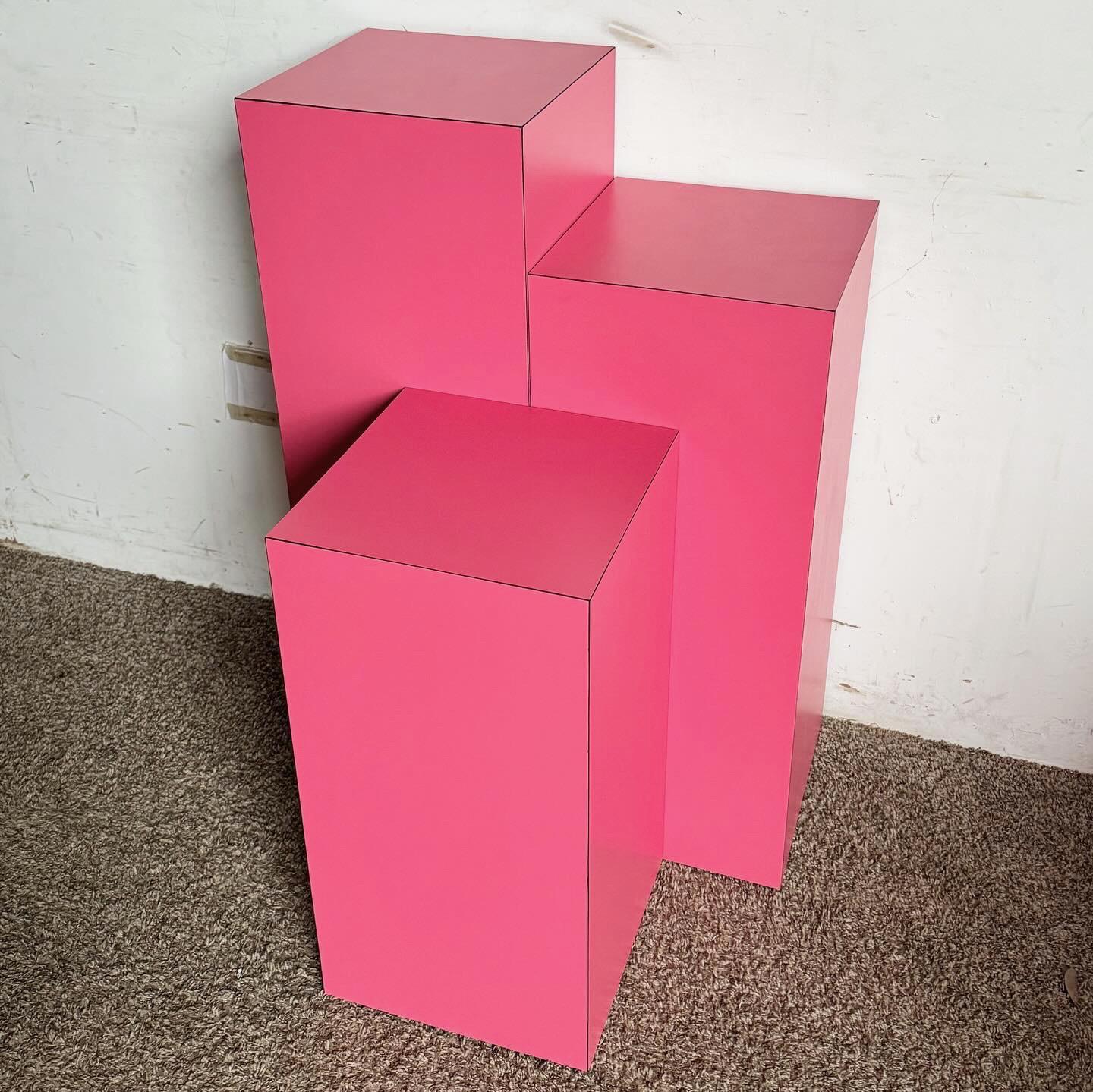 Brighten your home with the Postmodern Hot Pink Matte Laminate Ascending Rectangular Prism Pedestal Set Tables. This set of three, featuring vibrant hot pink finishes, adds a playful touch to any space. With ascending heights of 36.25‚Äù, 30.25‚Äù,